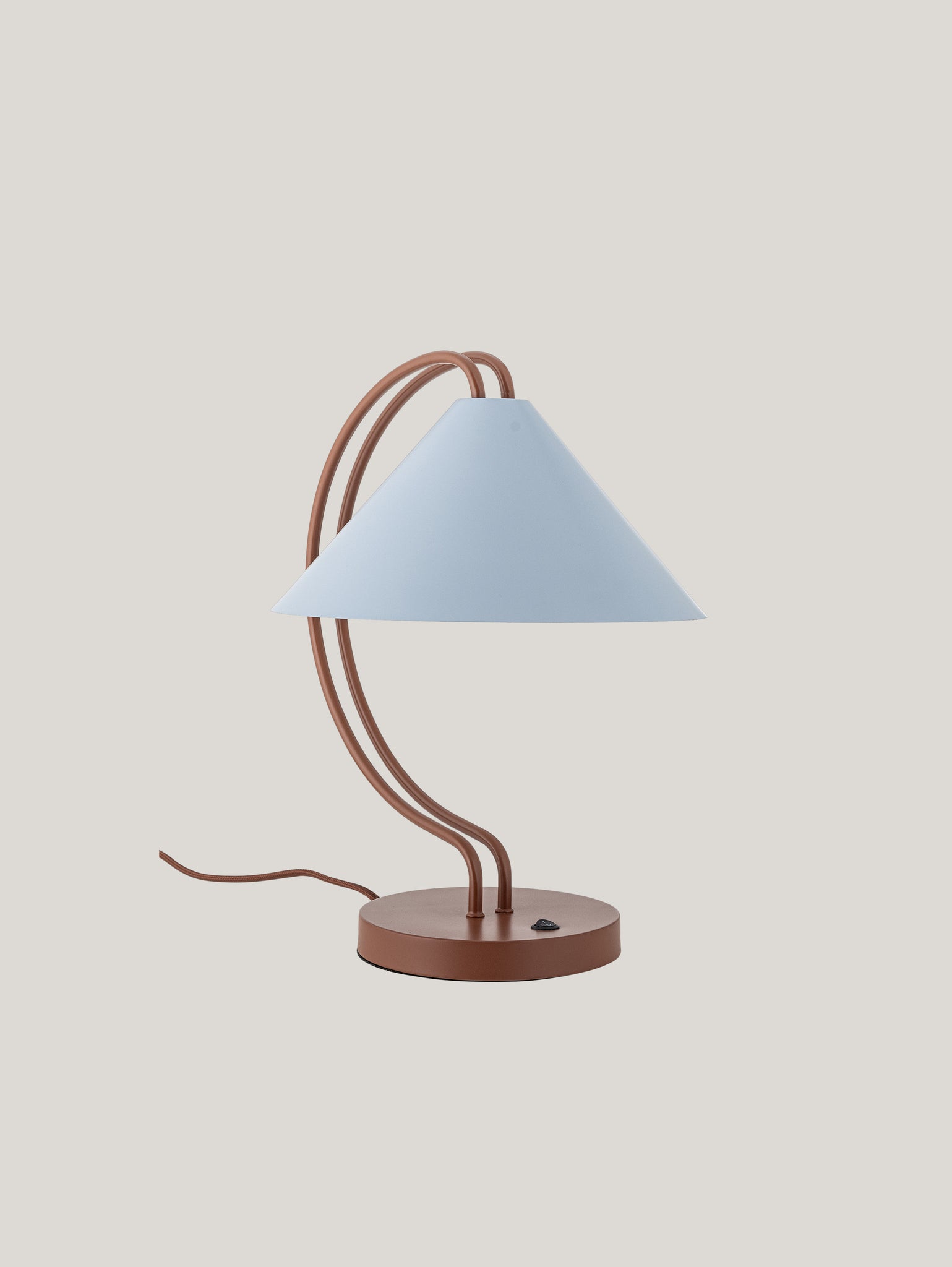 La lampada da tavolo Janya di Divani.Store è una lampada da tavolo chic dal design minimalista e moderno. Include una base circolare marrone e uno stelo marrone curvo, completato da un paralume conico azzurro. Un cavo di alimentazione marrone con un piccolo pulsante di accensione nero si estende dalla base, su uno sfondo grigio chiaro.