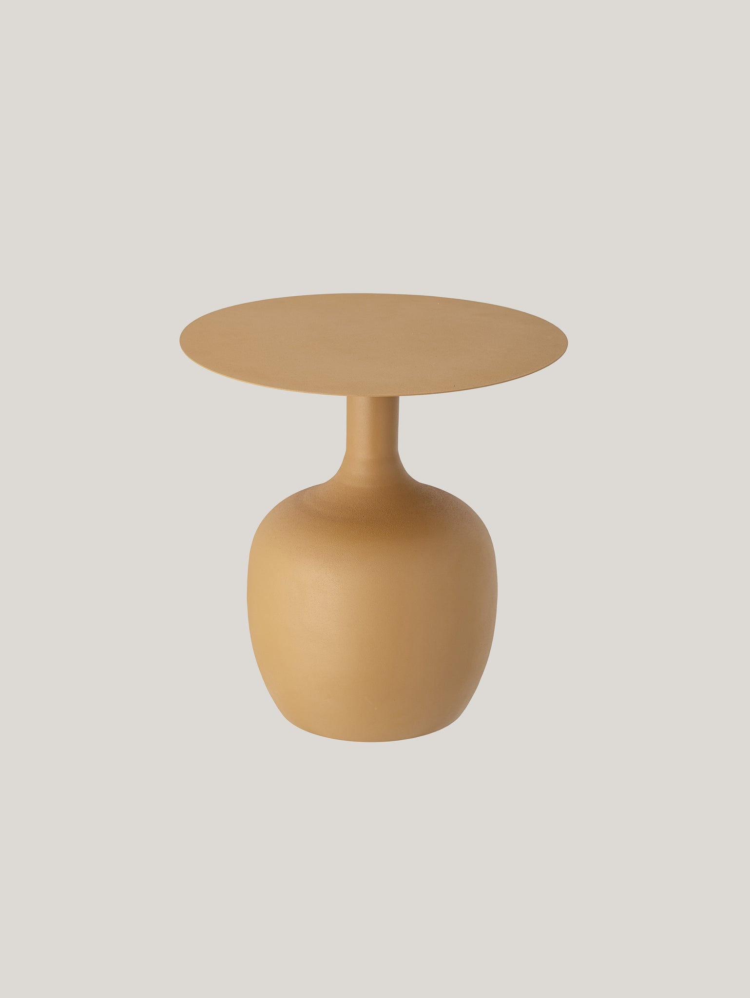 Un piccolo e moderno tavolino decorativo di design rotondo Ayah in metallo giallo caldo di Divani.Store. Il tavolo presenta un piano circolare liscio e piatto e una base robusta e arrotondata a forma di vaso, che incarna un design nordico minimalista e contemporaneo. Uno sfondo bianco sporco semplice evidenzia la forma elegante del tavolo e il suo caldo colore giallo.