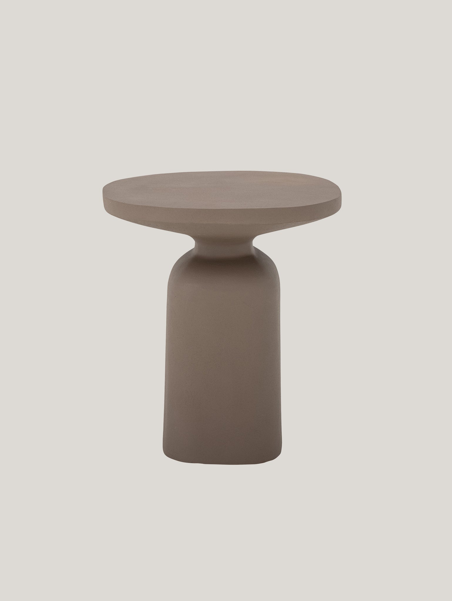 Il tavolino scultoreo in metallo e alluminio fatto a mano Millan colore terra di Divani.Store è un tavolino moderno beige con piano piatto e rotondo e base cilindrica. Il suo design minimalista mette in mostra curve eleganti e una finitura opaca, che risalta elegantemente su uno sfondo grigio chiaro e semplice.