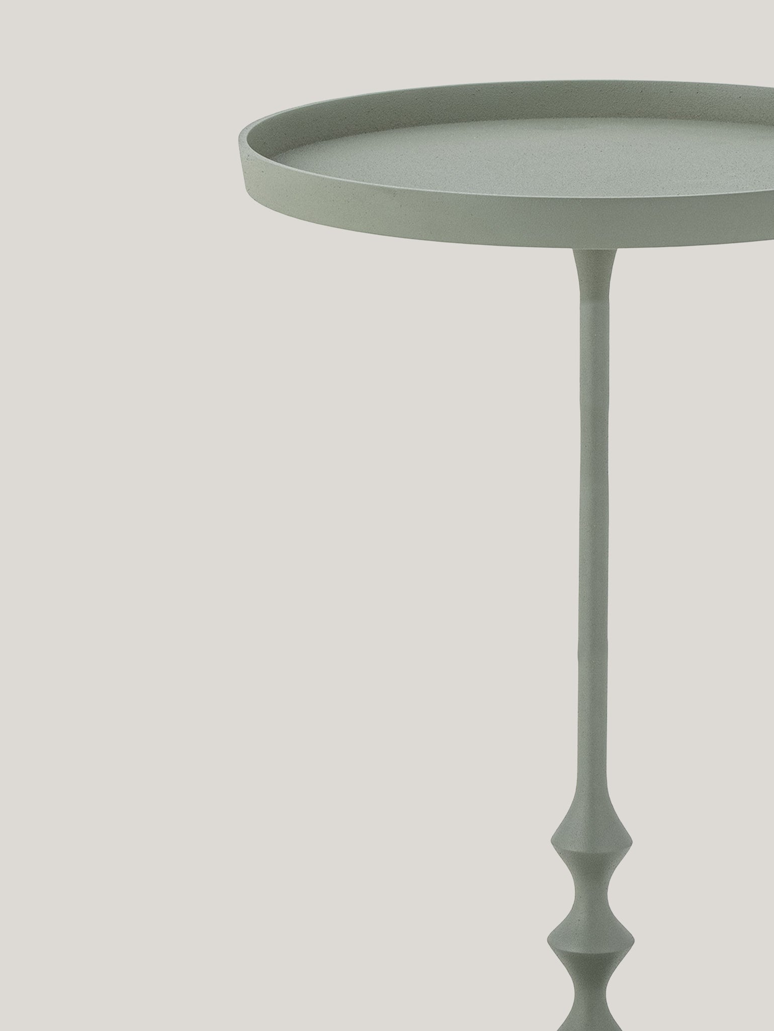 L'Anjou tavolino da appoggio elegante in metallo verde di Divani.Store presenta un design minimalista con il suo piano circolare verde chiaro e la base sottile e finemente intagliata del piedistallo. La sua superficie liscia verde polvere contrasta magnificamente con uno sfondo bianco sporco, enfatizzando il design semplice ma elegante del tavolo.