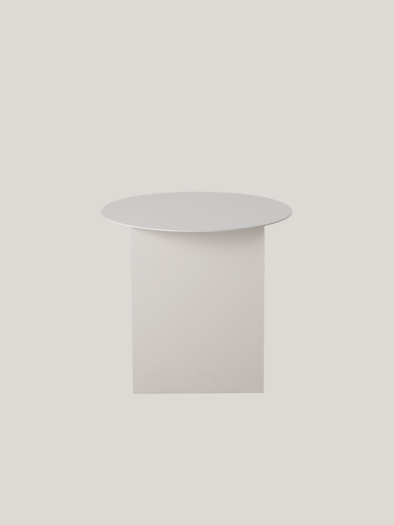 Un tavolino minimalista Cher scandinavo di Divani.Store con piano rotondo bianco e base quadrata è posizionato su uno sfondo grigio chiaro e morbido. Il design elegante abbraccia lo stile nordico, evidenziando linee pulite e semplicità, con un porta riviste integrato.