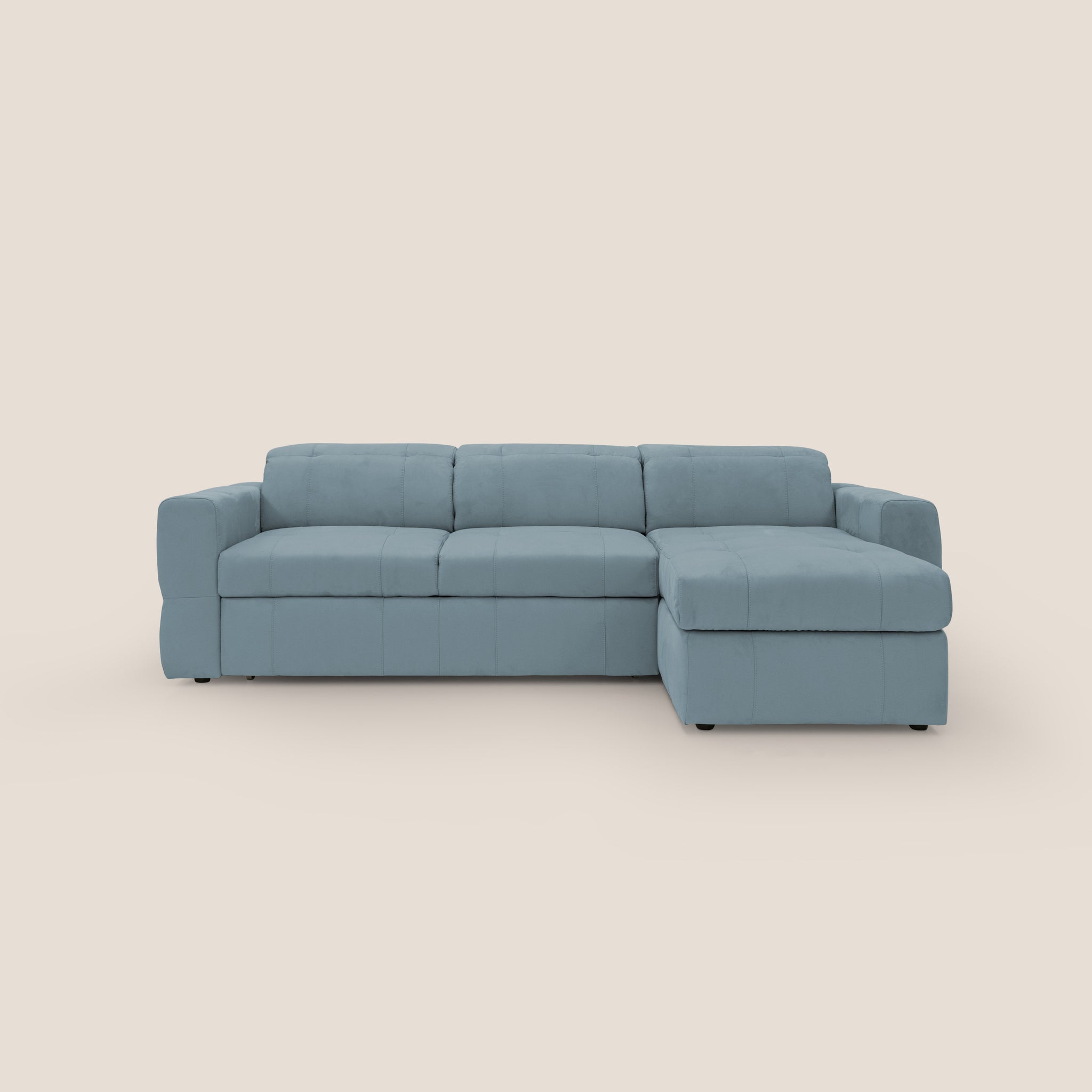 Un divano angolare Kronos azzurro contemporaneo di Divani.Store, con chaise longue sul lato destro e su uno sfondo beige semplice. Realizzato in Italia, questo divano sofisticato vanta un design moderno con tre cuscini di seduta e braccioli quadrati per un aspetto elegante e attuale.