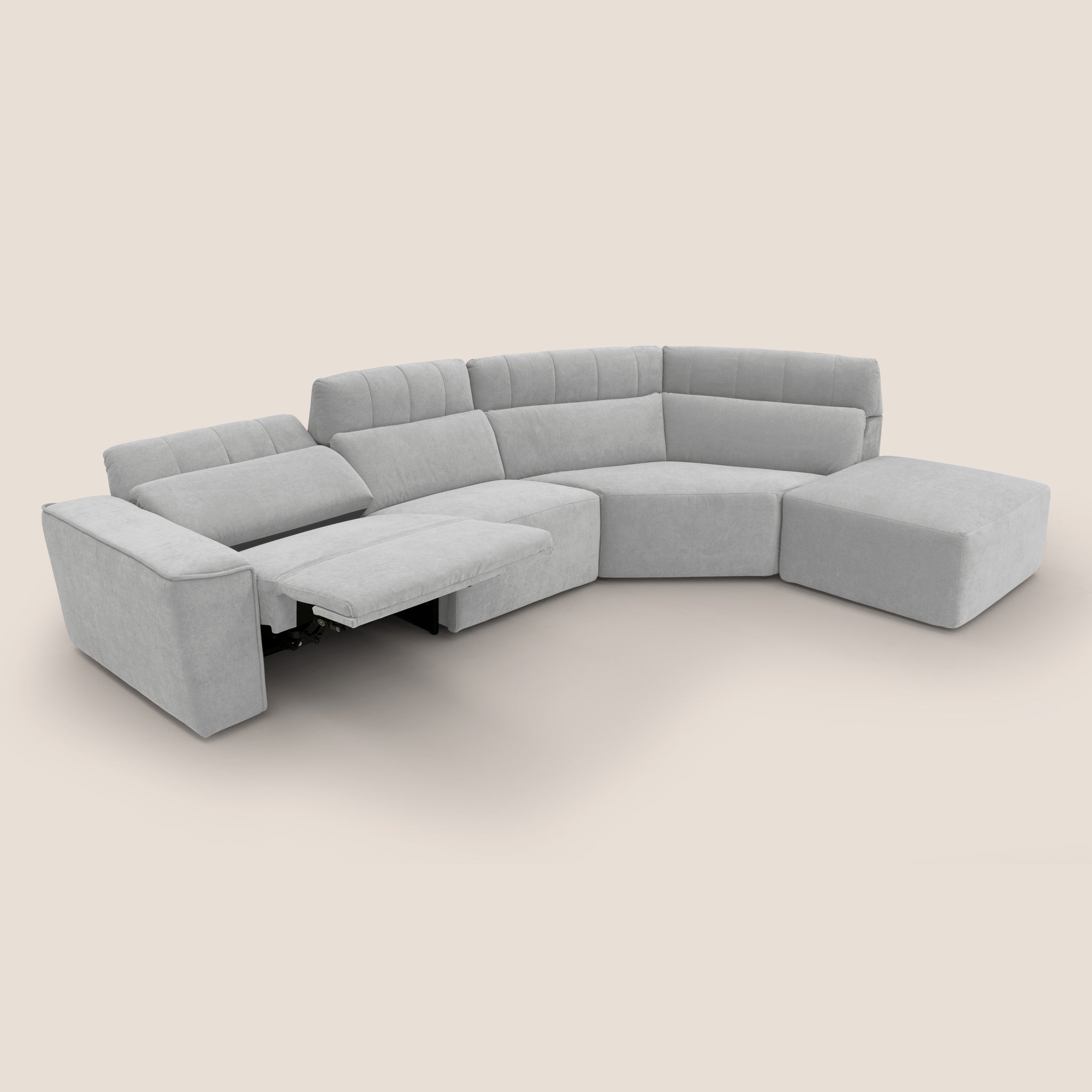 Un divano modulare contemporaneo in grigio chiaro, il Clark Divano angolare con relax elettrico di Divani.Store presenta un comodo sedile reclinabile elettrico sul lato sinistro con un'estensione poggiapiedi visibile. Rivestito in tessuto smacchiabile impermeabile T17 GRIGIO, presenta un'imbottitura morbida e include un pouf sul lato destro, il tutto su uno sfondo semplice e neutro.