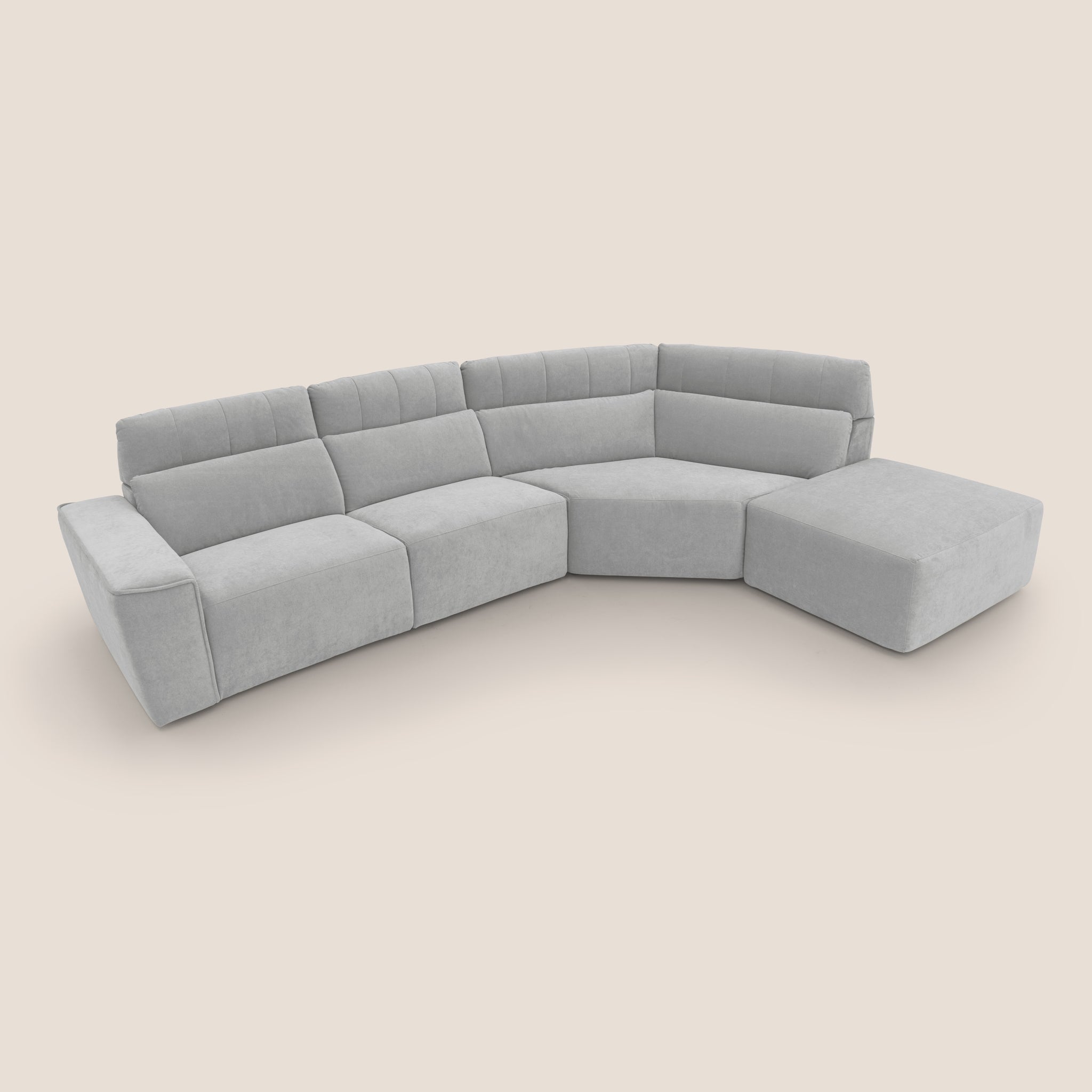 Divano angolare Clark grigio chiaro con tre sezioni di seduta principali e un pouf abbinato, realizzato da Divani.Store in tessuto smacchiabile impermeabile T17. Il design contemporaneo presenta schienali trapuntati e linee pulite e dritte, su uno sfondo color crema semplice per un look sofisticato.