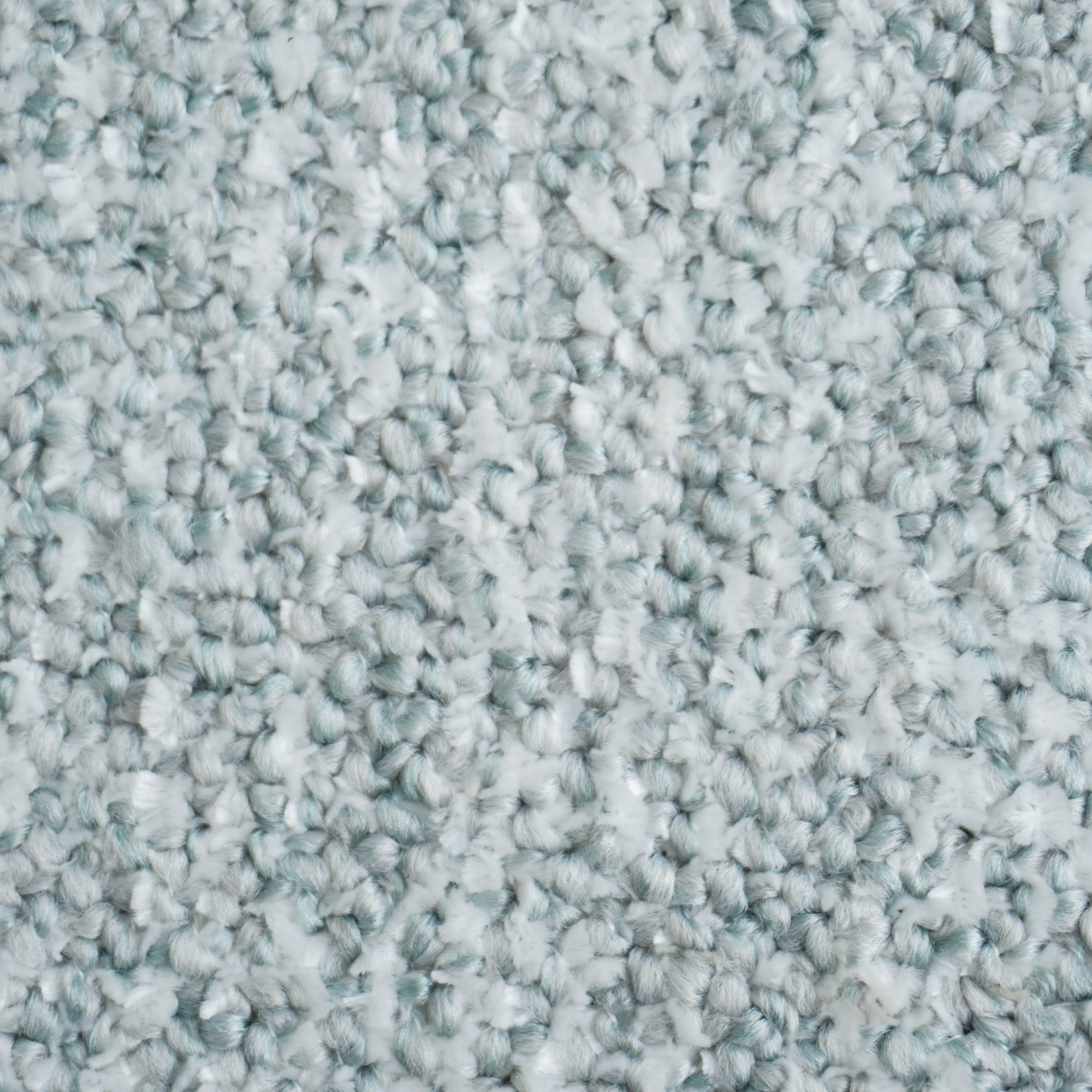 Primo piano del tappeto Personalizzazione in T29 di Divani.Store, caratterizzato da fibre a maglie strette nei colori grigio chiaro e bianco. La superficie morbida e leggermente irregolare presenta sottili sfumature maculate per un aspetto accogliente, senza macchie o disegni visibili.