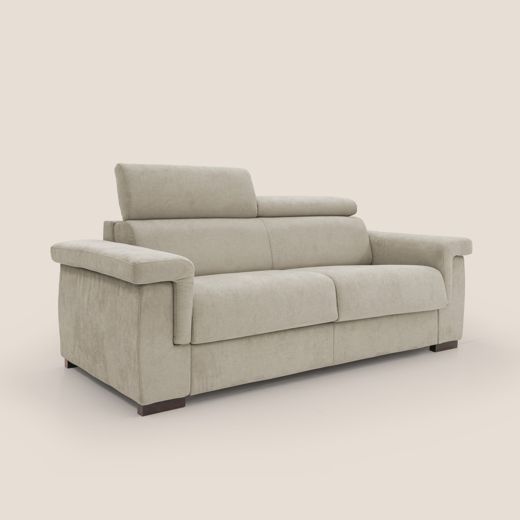 Il divano letto Bjorn di Divani.Store è rivestito in tessuto beige impermeabile e presenta poggiatesta regolabili con ampi braccioli. Il suo design minimalista è completato da piccole gambe in legno scuro, su uno sfondo semplice e chiaro, che evidenziano la squisita artigianalità dell'artigianato italiano.