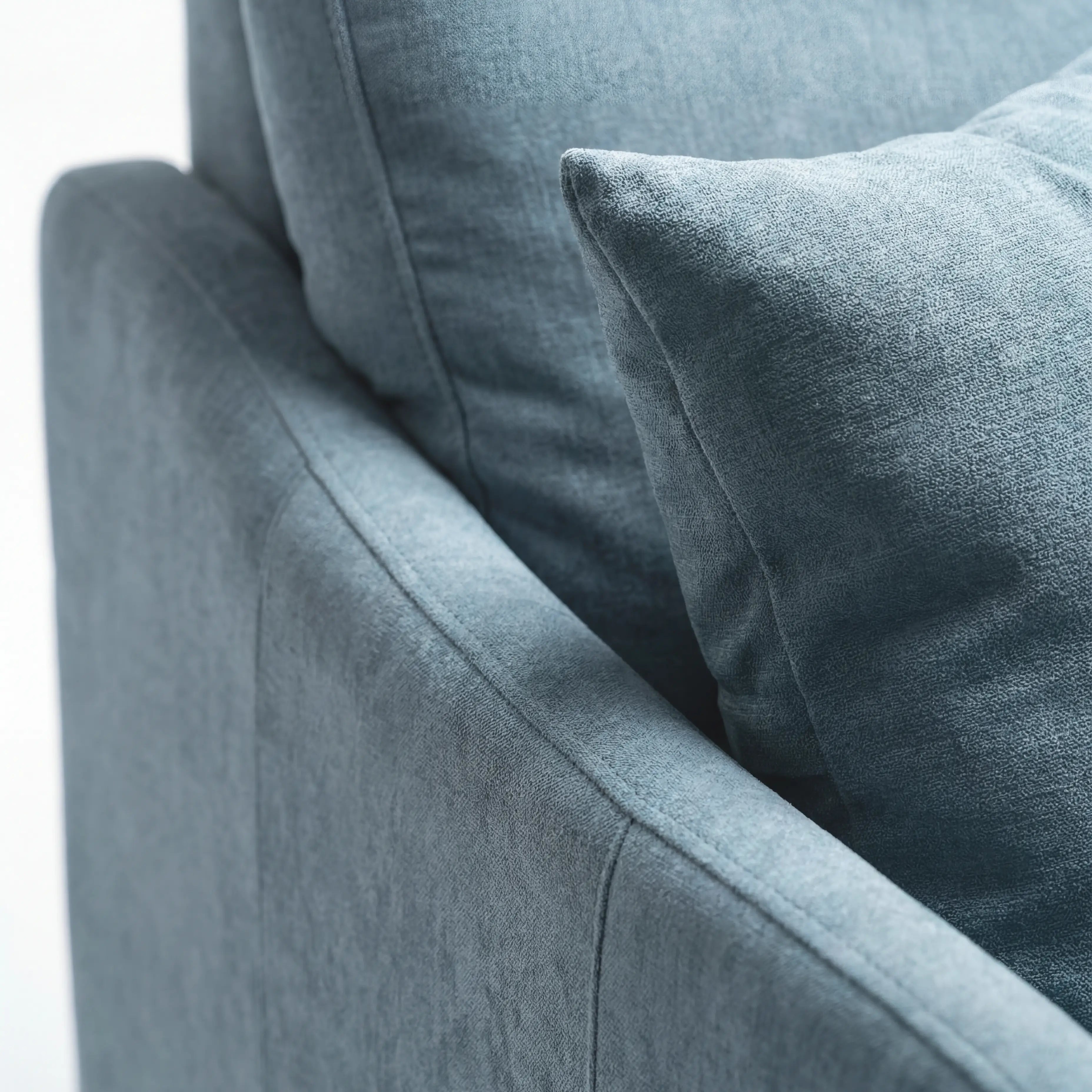 Primo piano del divano letto a 3 posti Lodovico di Divani.Store, rivestito in tessuto azzurro resistente alle macchie e certificato Oeko-Tex. L’attenzione ai dettagli dei braccioli, dello schienale, dei portacuscini e dei cuscini ne esalta il comfort avvolgente e le linee pulite.