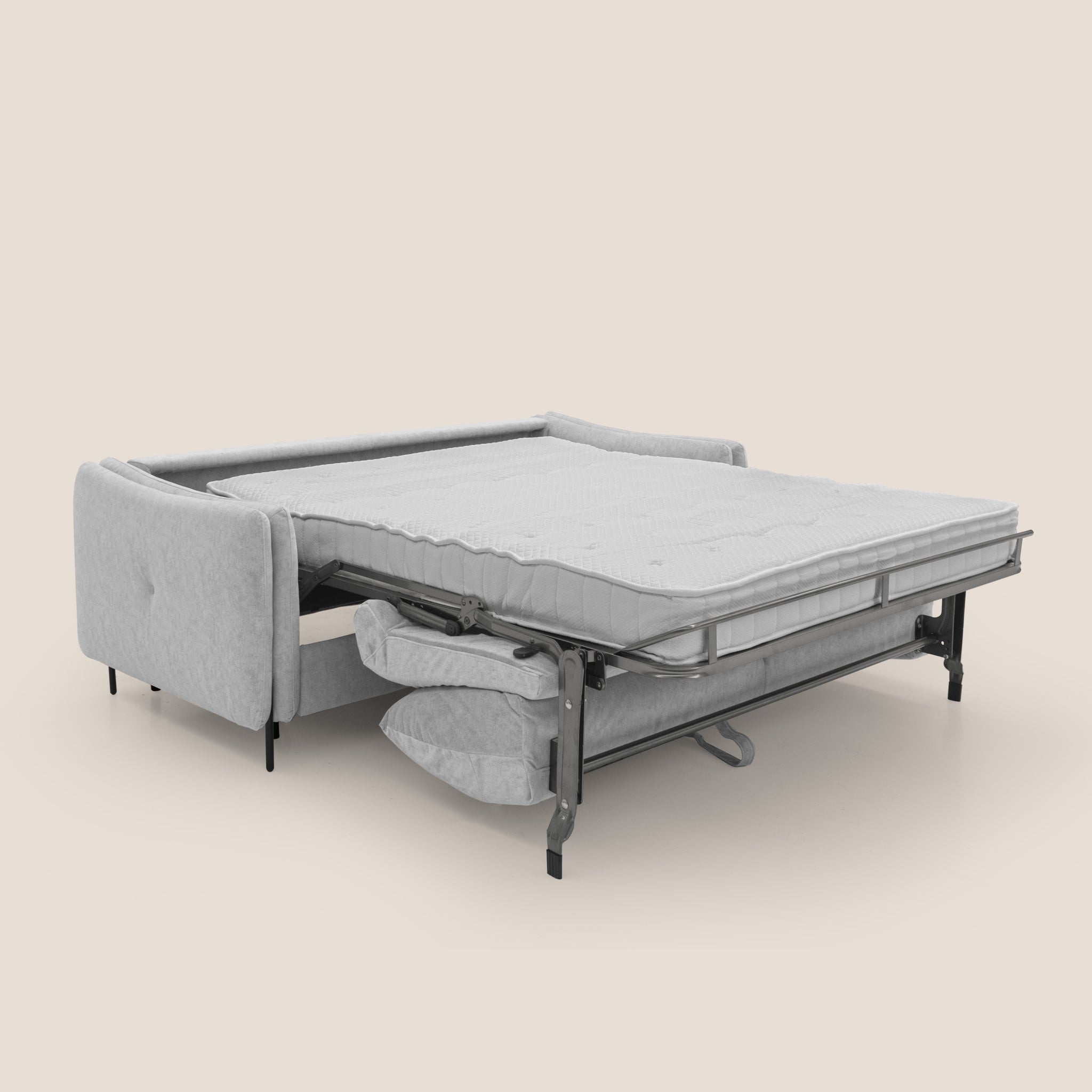 Il divano letto Gregory di Divani.Store è esposto in posizione aperta, con un materasso disposto ordinatamente su una struttura in metallo. Il divano grigio chiaro, realizzato in microfibra impermeabile con effetto velluto, presenta un design semplice e moderno con linee pulite e poggia su gambe nere. Un set di biancheria da letto piegato può essere visto sotto la struttura, indicando ulteriore spazio di archiviazione per un comfort superiore.