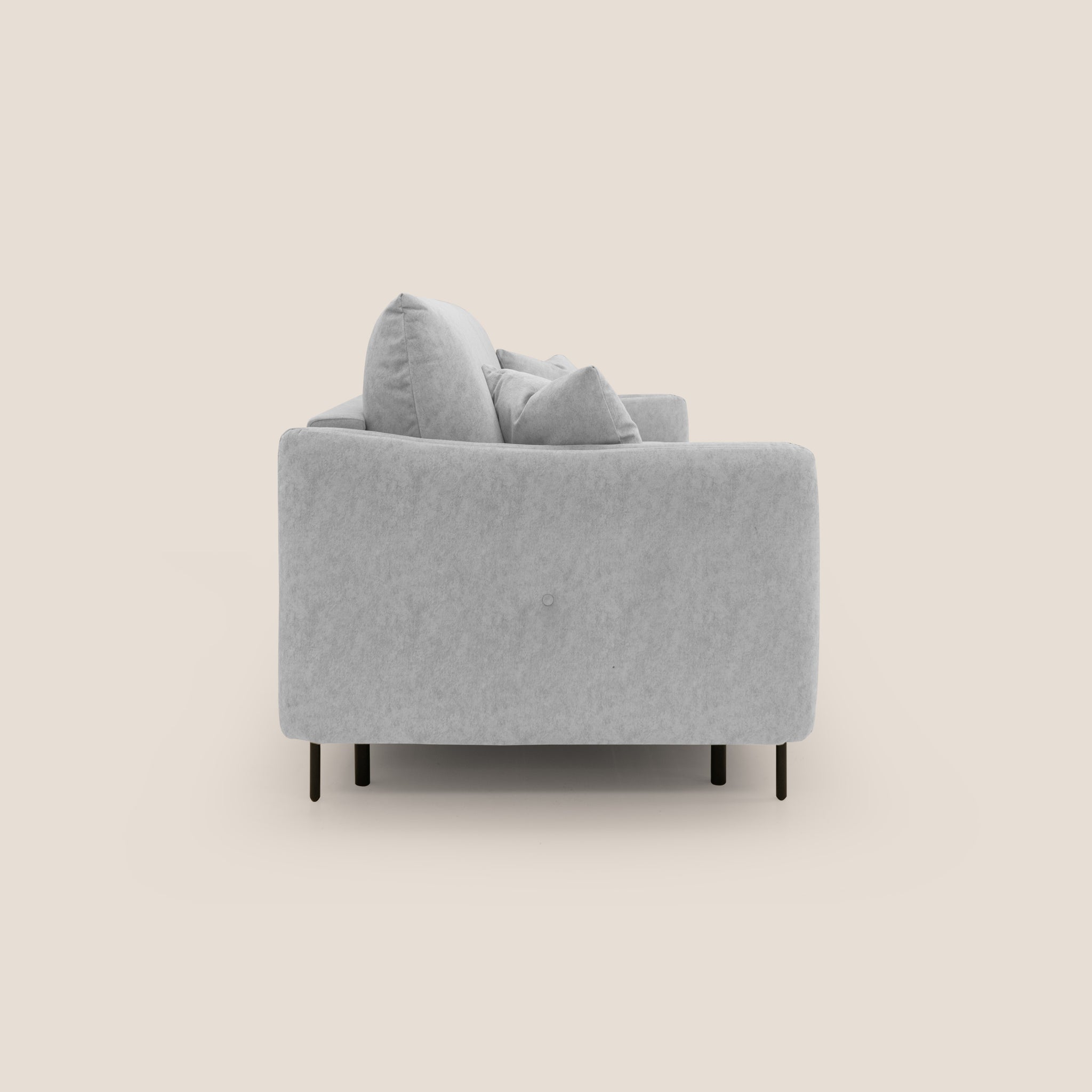 Vista laterale del divano letto Gregory di Divani.Store, un moderno divano grigio chiaro con cuscini morbidi su uno sfondo beige semplice. Questo divano letto offre un comfort superiore con il suo design minimalista e le linee dritte, con grandi cuscini dello schienale e cuscini laterali più piccoli, tutti sostenuti da sottili gambe nere. Il divano misura 196 cm di lunghezza ed è dotato di un materasso alto 18 cm in microfibra impermeabile con effetto velluto.