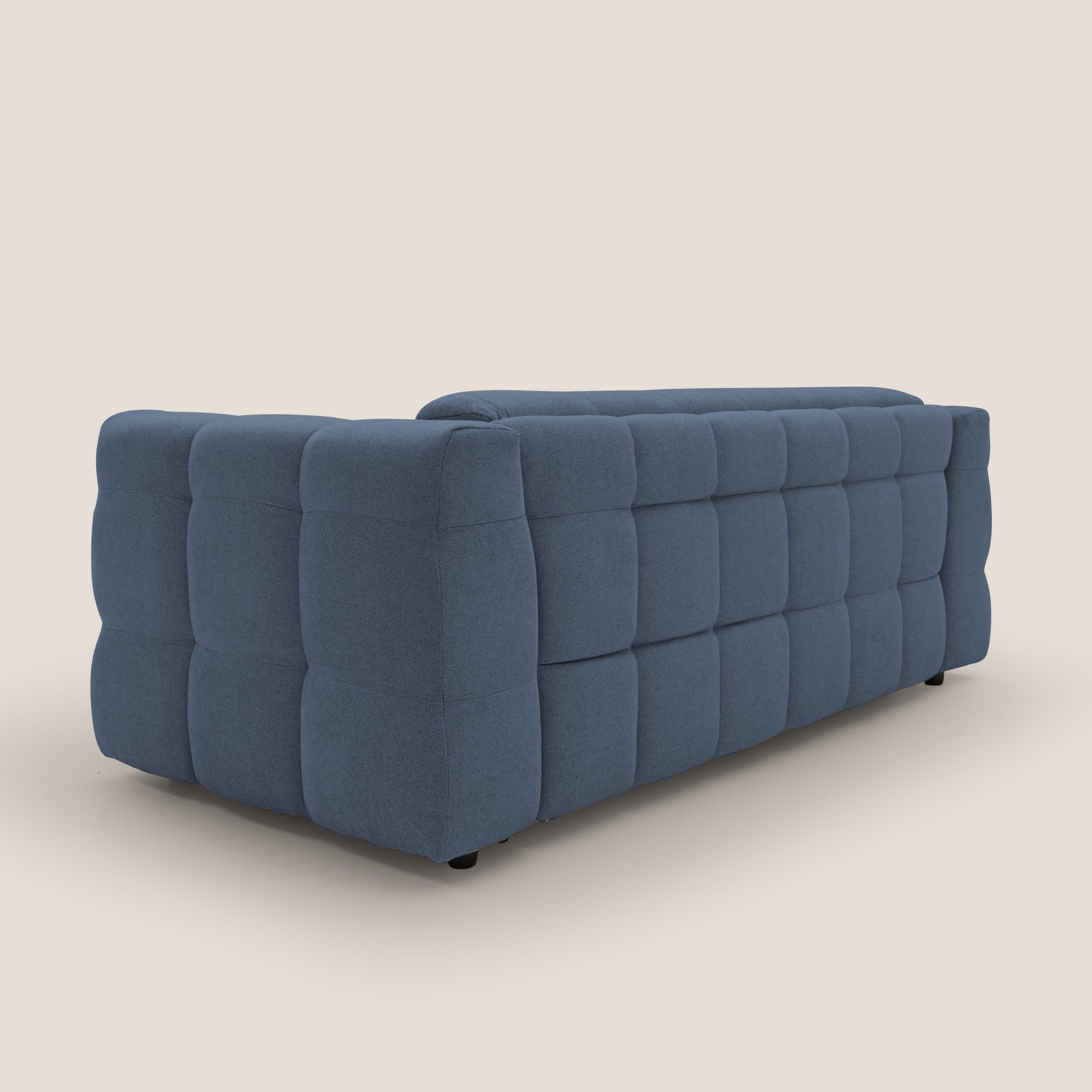 Un divano moderno blu di Divani.Store trasuda comfort con uno schienale e lati trapuntati su uno sfondo beige. Il rivestimento impermeabile bouclet presenta un motivo quadrato per uno stile. Visto di sbieco, questo Tender Divano Letto matrimoniale mette in risalto la sua profondità e il suo innovativo design italiano.