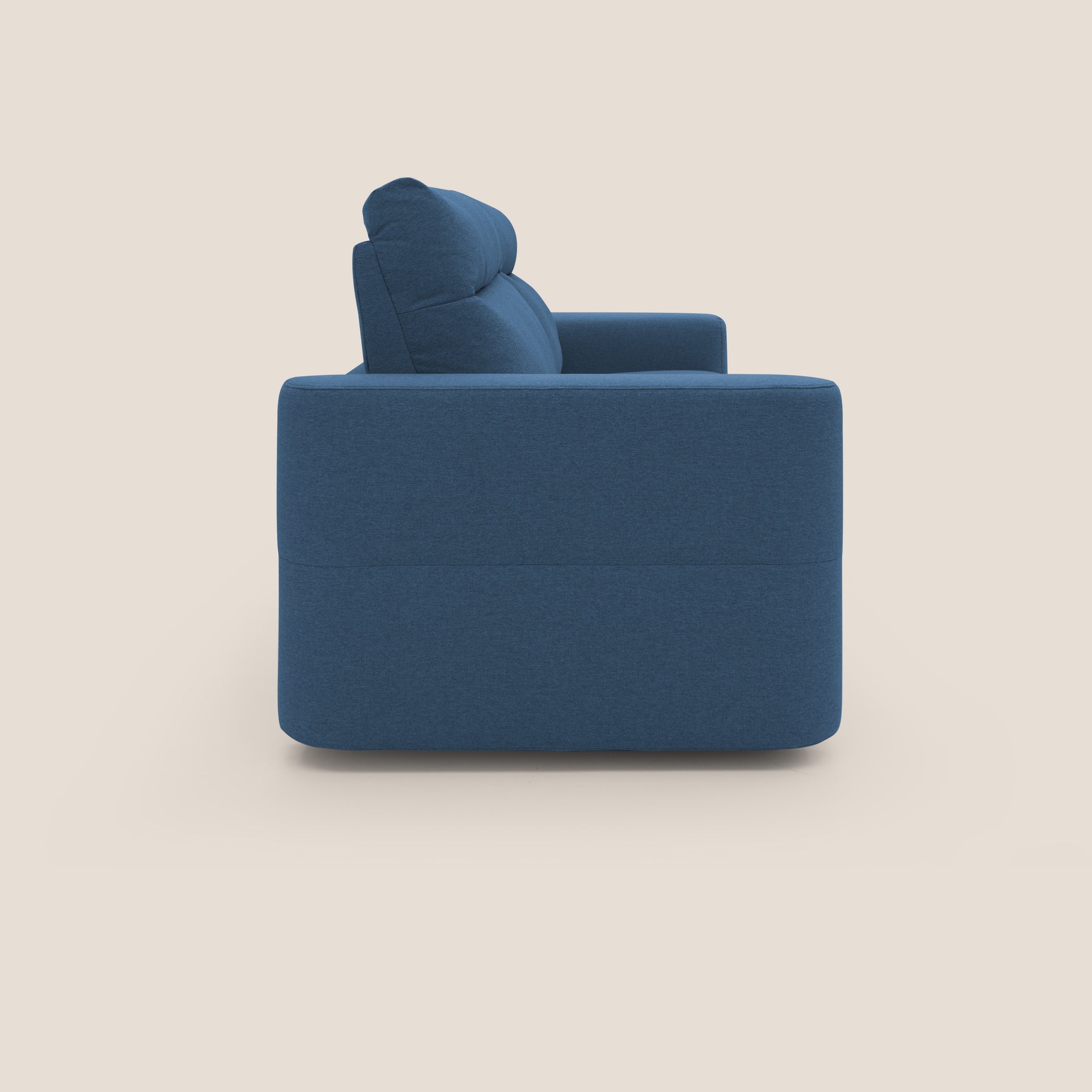 Vista laterale di un divano blu contemporaneo su uno sfondo beige chiaro. Il divano letto Cupido di Divani.Store presenta un design elegante e squadrato con schienale e seduta imbottiti per il massimo comfort. I braccioli spessi si allineano con lo schienale, mentre il morbido tessuto impermeabile leggermente strutturato che imita il cotone ne esalta il fascino, rappresentando l'eleganza italiana.