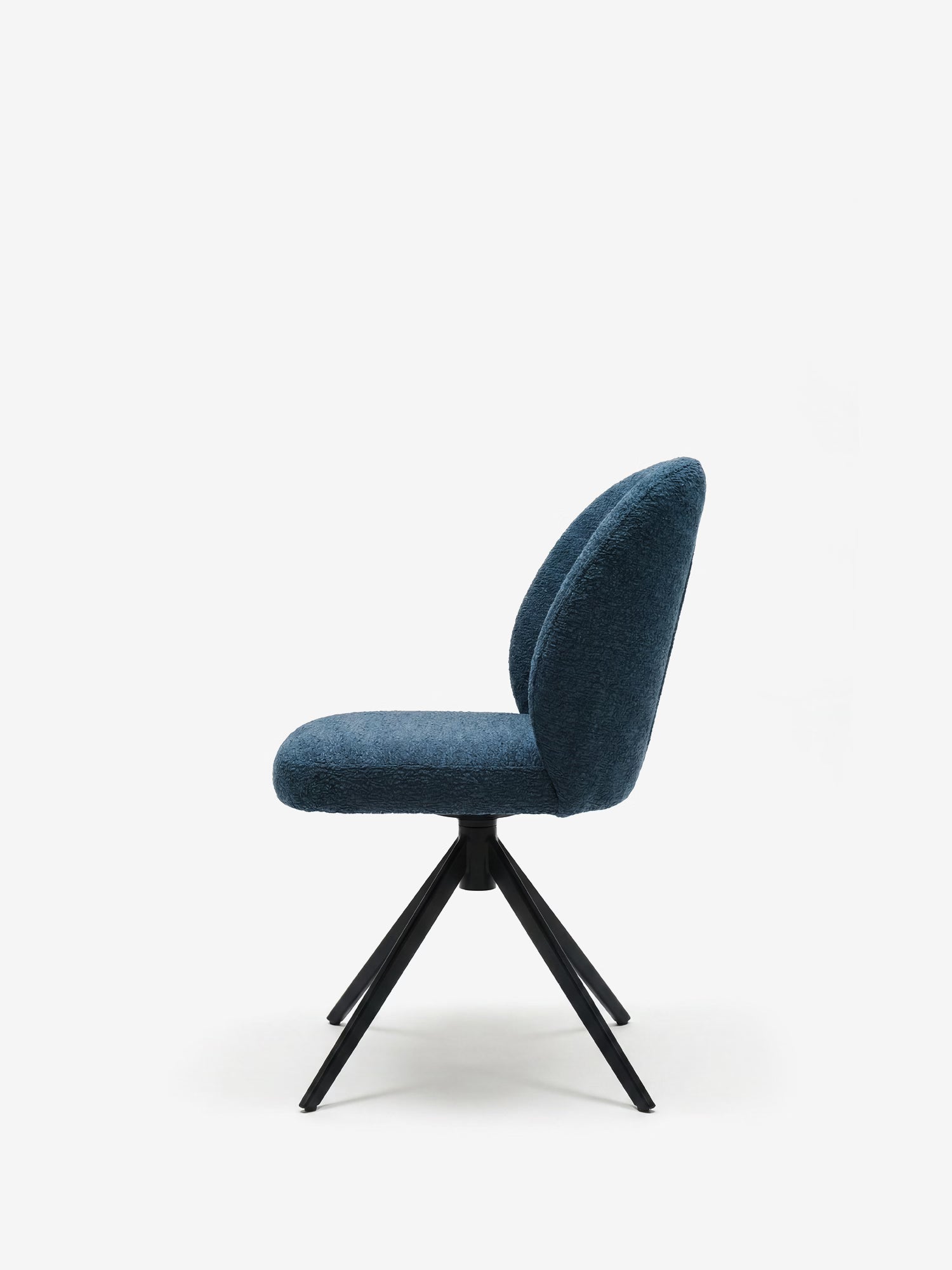 La sedia imbottita Alba di Divani.Store è realizzata con un tessuto effetto cotone certificato OEKO-TEX® in blu scuro e una moderna base a croce in metallo nero, che risalta su uno sfondo bianco a tinta unita, creando un look elegante e contemporaneo.