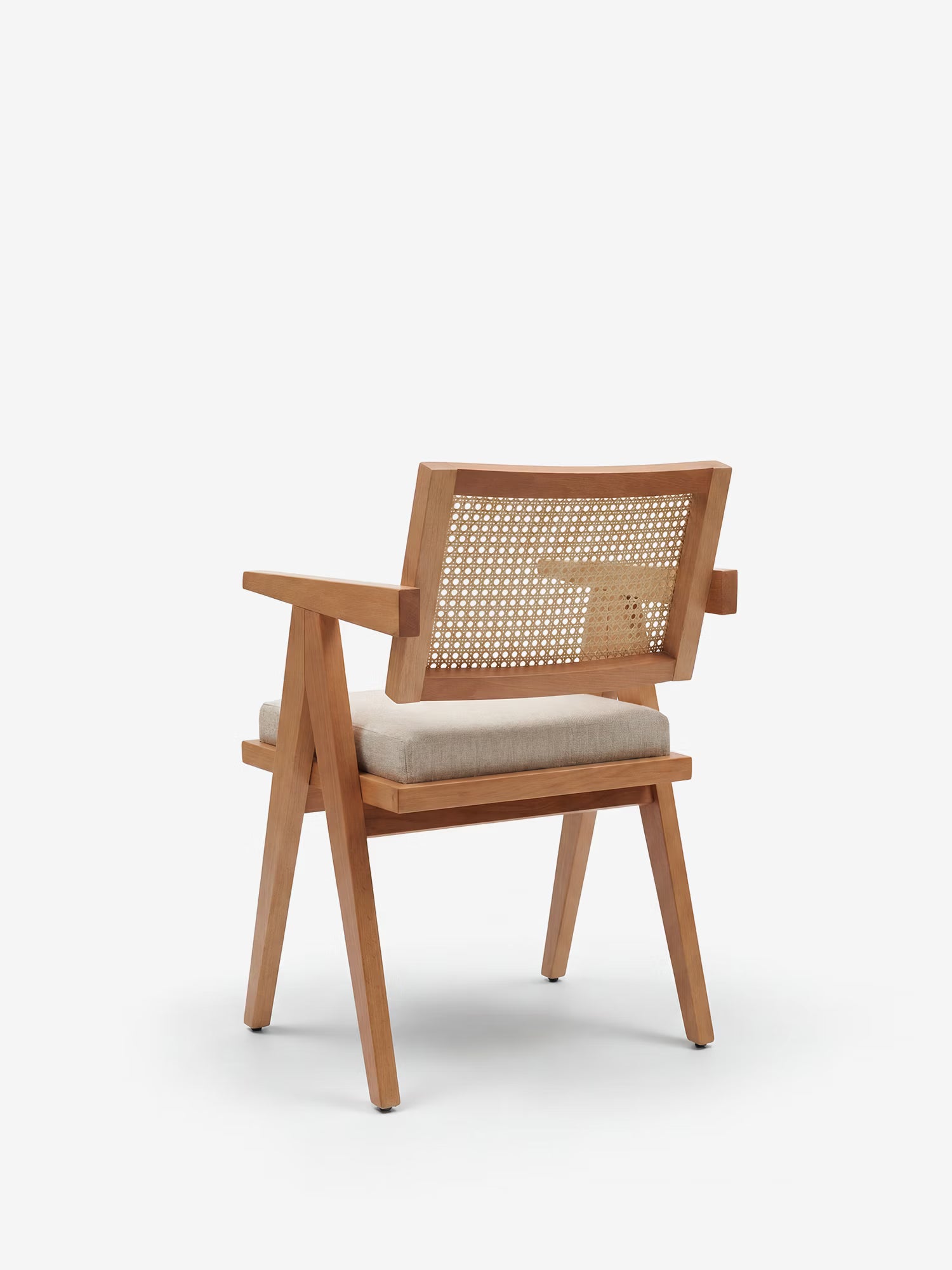 La sedia Antea con braccioli in rovere di Divani.Store, con schienale in rattan e seduta imbottita in tessuto misto cotone beige, presenta gambe inclinate, braccioli piatti ed è ritratta di spalle su uno sfondo bianco.