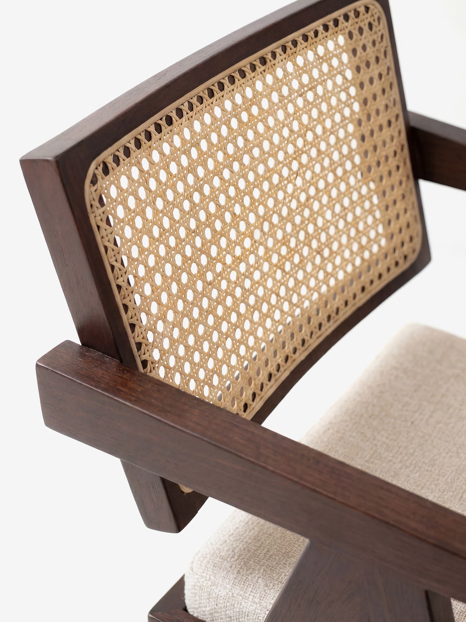 Primo piano della sedia Antea con braccioli in legno massello wengé di Divani.Store, caratterizzata da uno schienale esagonale in rattan e da una seduta imbottita in misto cotone beige chiaro, su uno sfondo bianco a tinta unita.