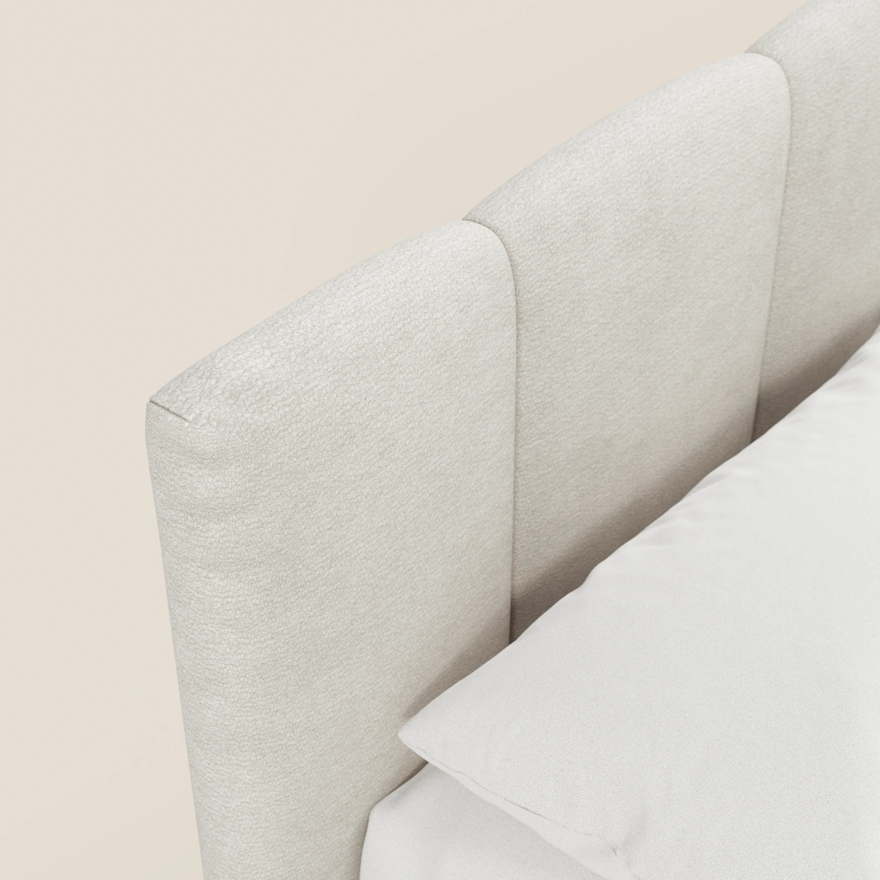 Primo piano del letto imbottito ARKAM di Letti.store, caratterizzato da una testiera a pannelli verticali in tessuto certificato Oeko-Tex®. Il cuscino bianco e la biancheria da letto completano il suo design shabby chic, arricchito da un pratico vano contenitore.