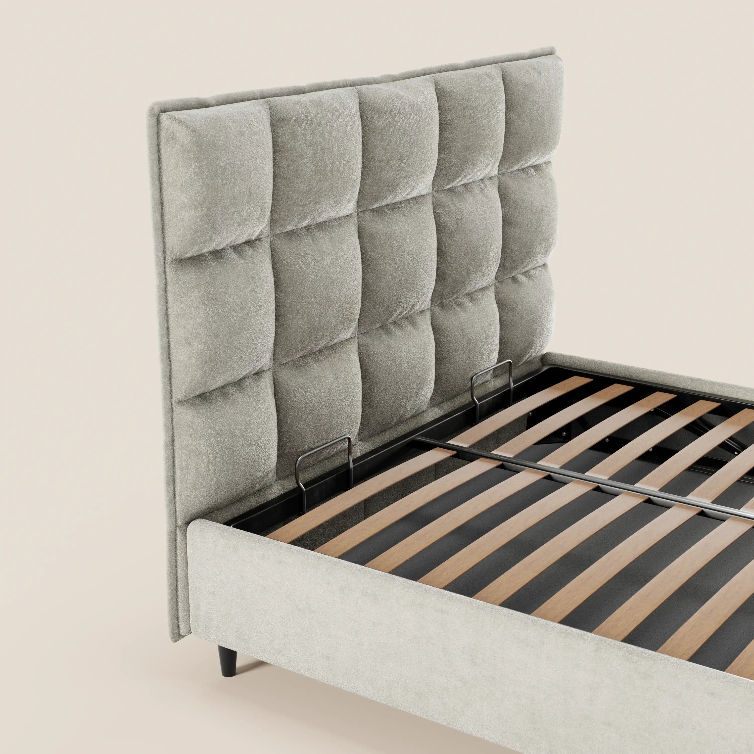 Il letto imbottito AURO con contenitore di Letti.store presenta una testiera alta capitonné in ciniglia grigio chiaro certificata Oeko-Tex®, doghe in legno, morbido rivestimento in tessuto con bordi arrotondati e sottili gambe nere. Materasso e biancheria da letto non inclusi.