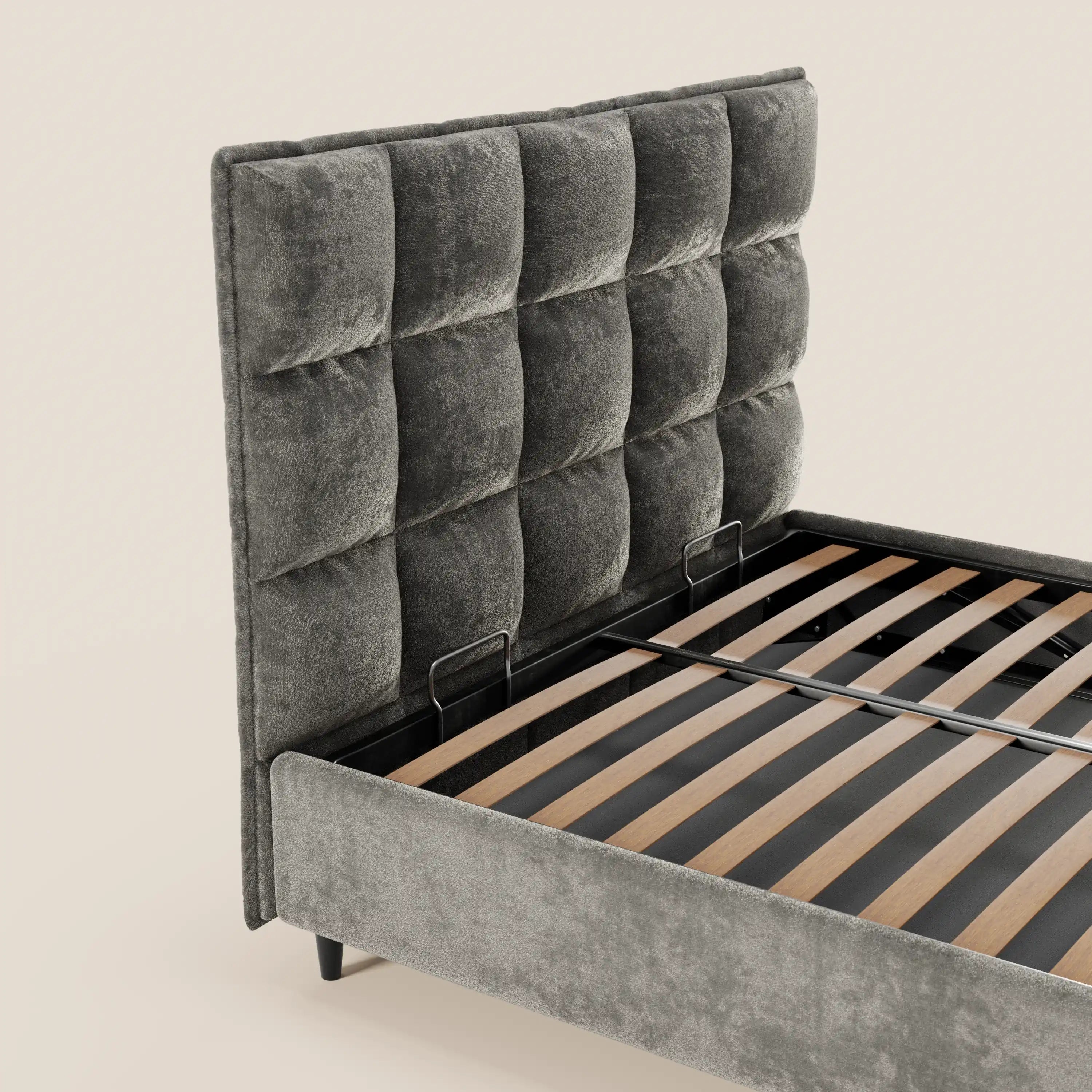 Il letto imbottito AURO di Letti.store presenta una testiera alta e rettangolare in ciniglia capitonné certificata Oeko-Tex® e una struttura imbottita grigia abbinata con doghe in legno a vista, raffigurata su uno sfondo beige chiaro a tinta unita.