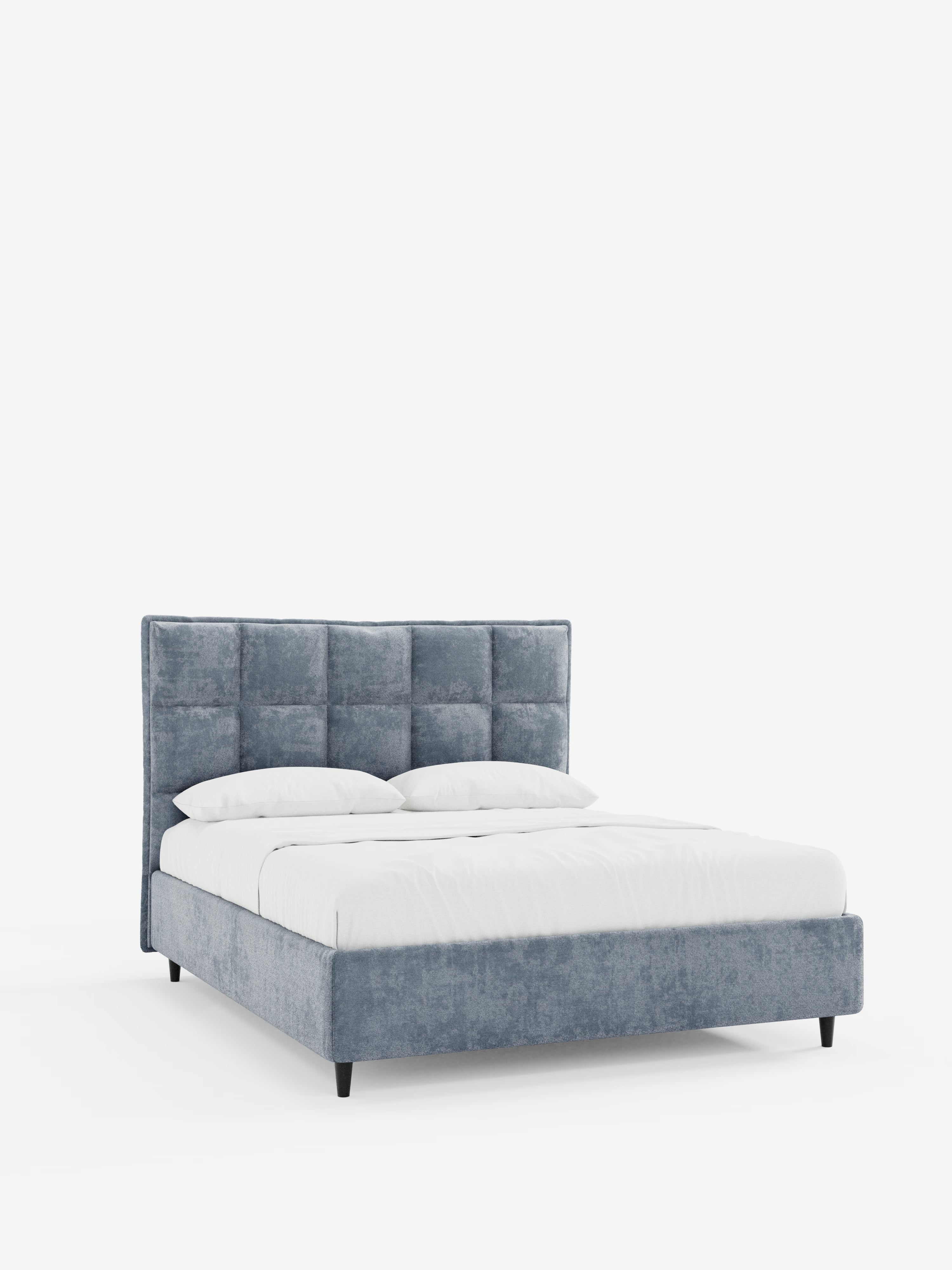 Un letto imbottito AURO in stile contemporaneo con contenitore e testiera alta capitonné in ciniglia Oeko-Tex® di Letti.store, caratterizzato da un'alta testiera imbottita blu-grigia con un elegante motivo a griglia e da una struttura coordinata. Il letto è rifatto con cura con biancheria da letto di un bianco candido e due cuscini, che risaltano su uno sfondo bianco a tinta unita.