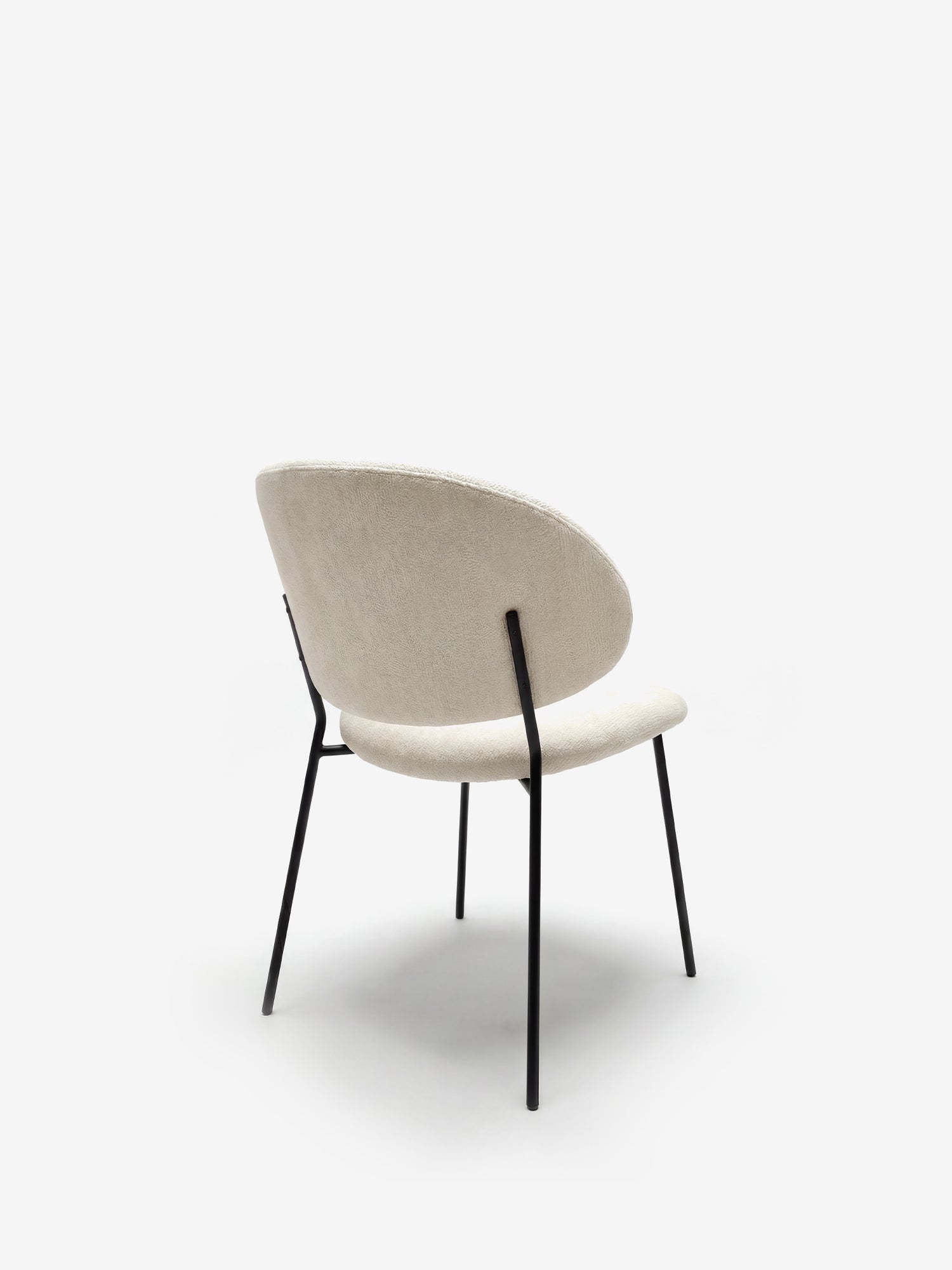 La sedia Bruma di Divani.Store, realizzata in elegante tessuto goffrato beige con schienale avvolgente e gambe sottili in metallo nero, presenta un design minimalista e contemporaneo su sfondo bianco.