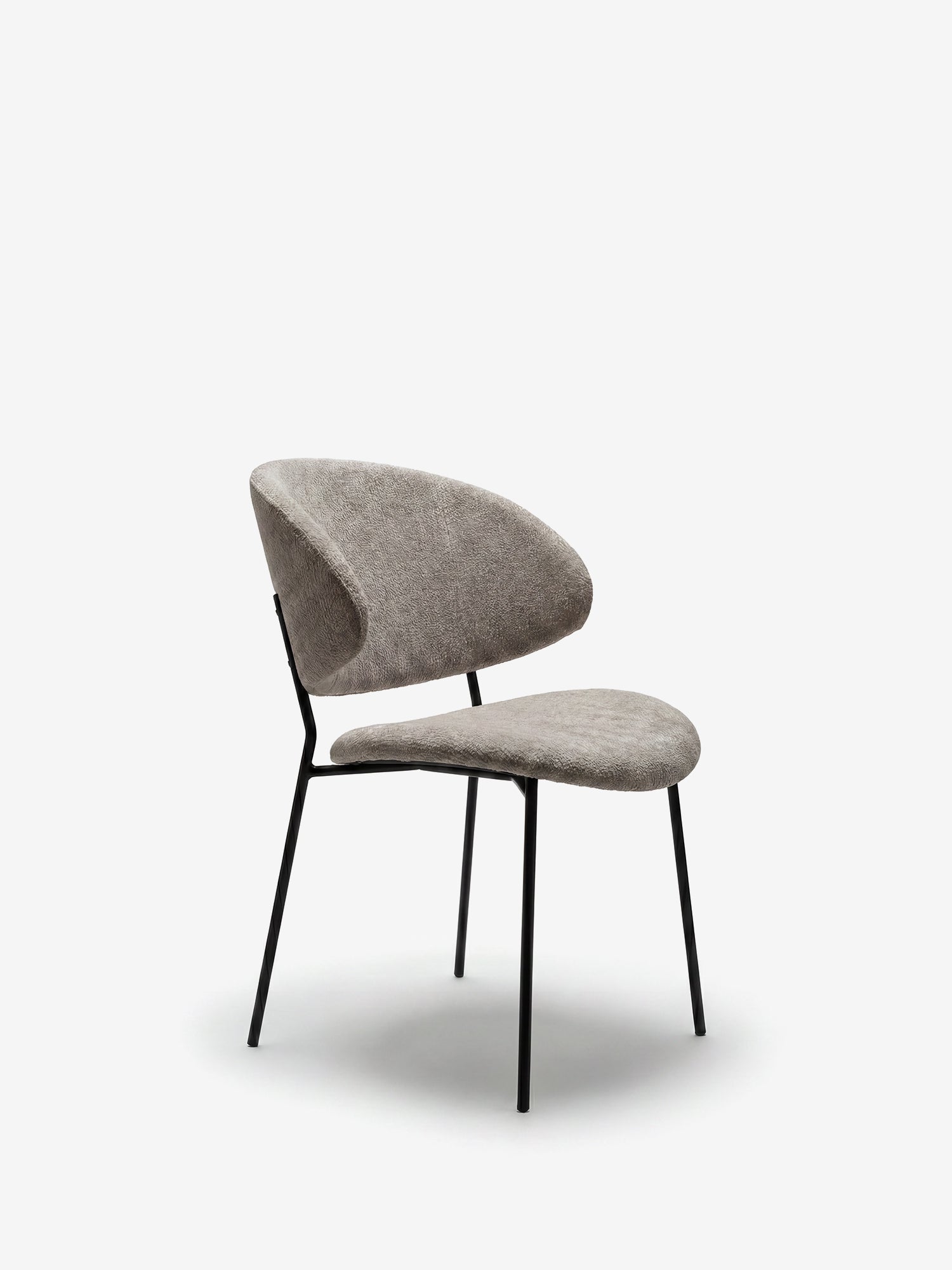 La sedia La Bruma di Divani.Store abbina un tessuto goffrato grigio a eleganti gambe in metallo nero. Il design minimalista e lo schienale avvolgente risaltano in uno stile contemporaneo su sfondo bianco.