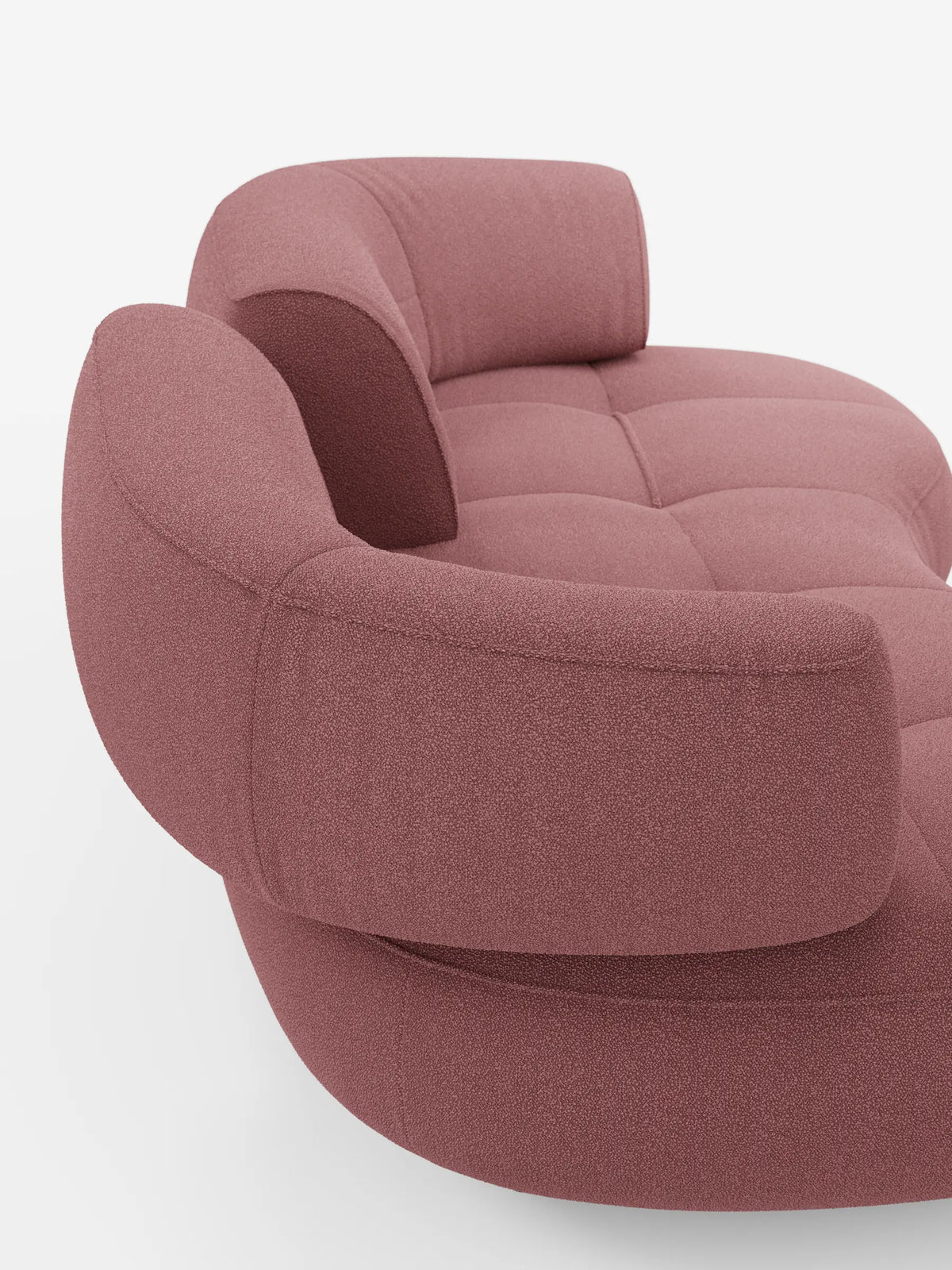 Il divano Divani.Store Croissant, un divano curvo a fagiolo a 3 posti con schienali traslanti, rivestito in morbido tessuto effetto cotone lavabile T33, è un divano curvo color rosa antico con seduta trapuntata e schienali arrotondati su uno sfondo bianco sporco.