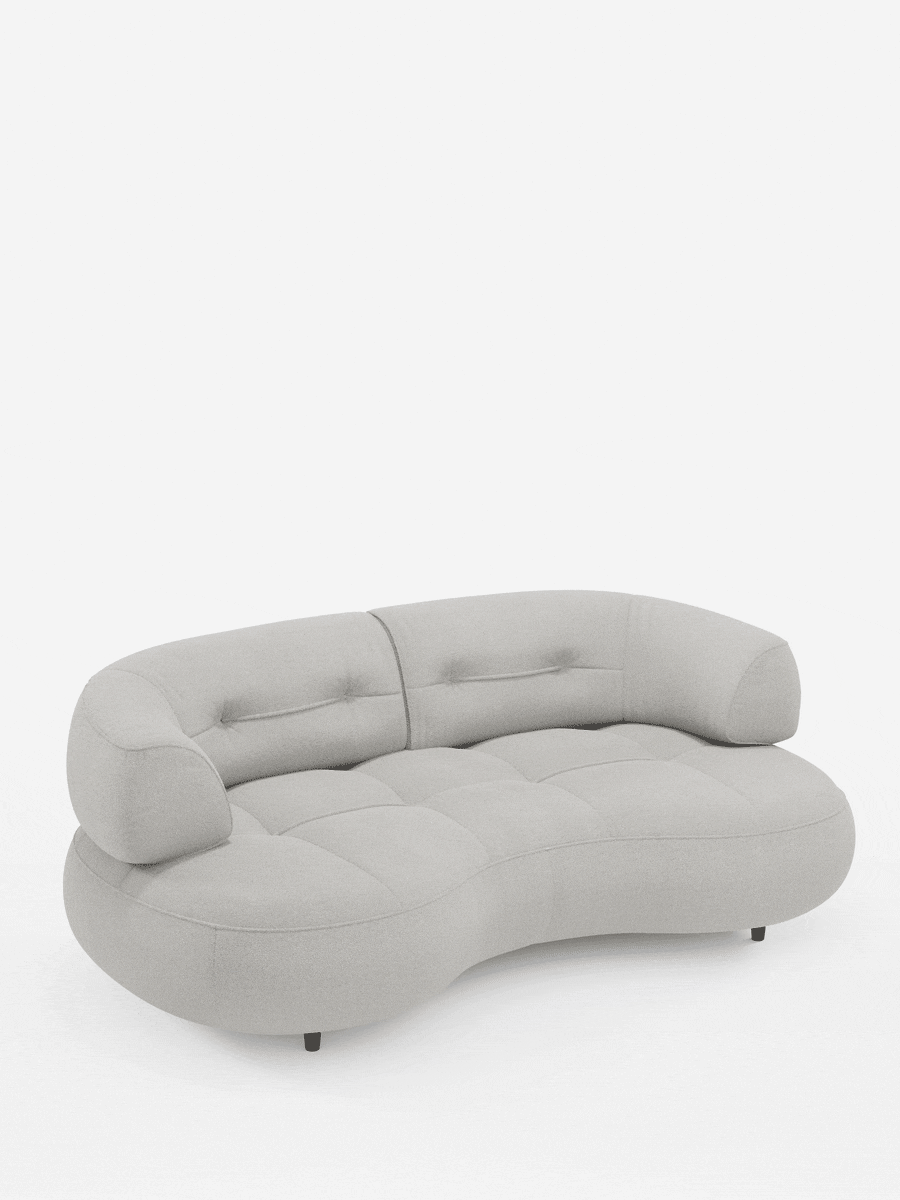 Un divano curvo a fagiolo a 3 posti “Croissant”, di colore grigio chiaro e dalla trama ruvida, con schienali traslanti in morbido tessuto effetto cotone lavabile T33, caratterizzato da un design a forma di fagiolo, dettagli trapuntati, braccioli arrotondati e piedini bassi e scuri su sfondo bianco.