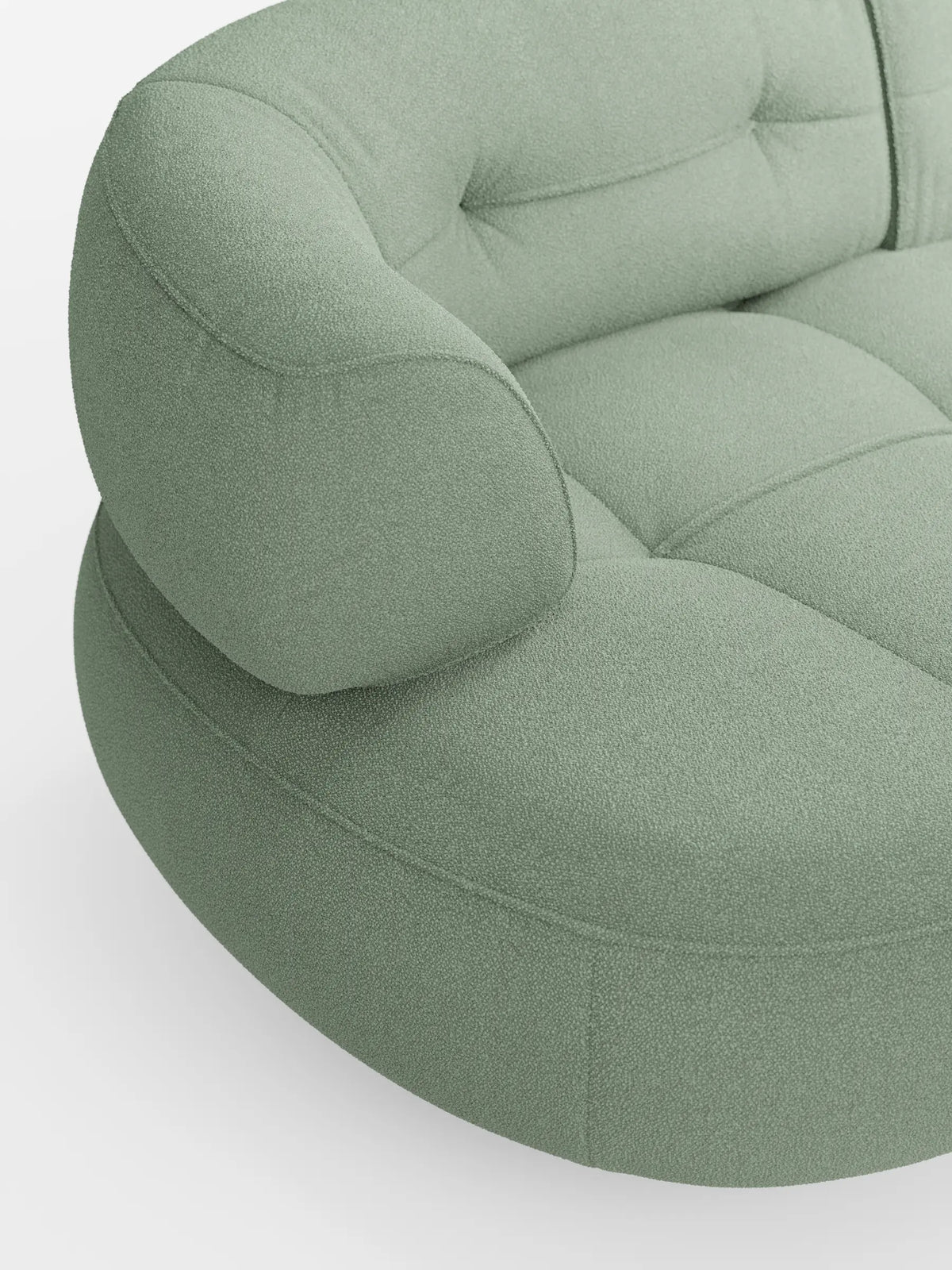 Un primo piano del divano Curvo a fagiolo “Croissant” color verde salvia, a 3 posti con schienali traslanti, rivestito in morbido tessuto effetto cotone smacchiabile T33, caratterizzato da braccioli arrotondati e dettagli trapuntati sulla seduta su uno sfondo bianco a tinta unita.