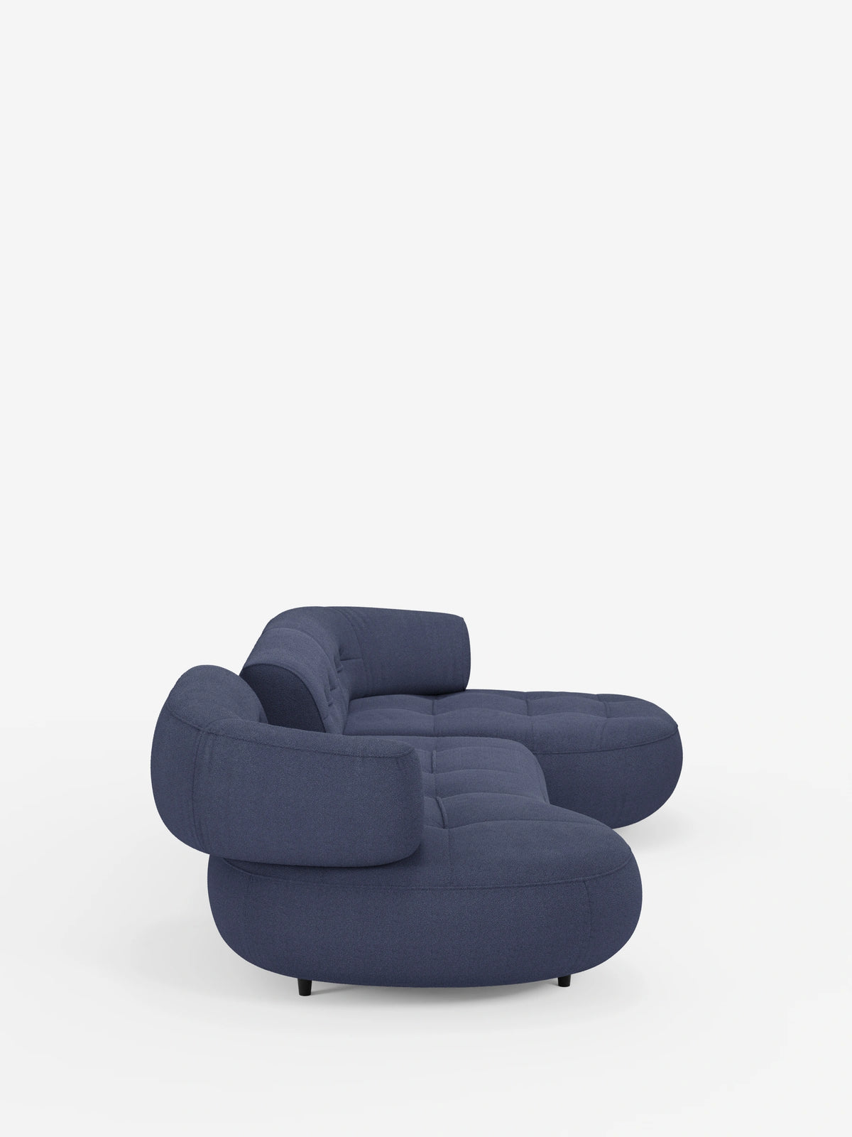 Un divano angolare “Croissant” blu navy, dal design a forma di fagiolo e con schienali scorrevoli, rivestito in morbido tessuto effetto cotone smacchiabile T33, caratterizzato da bordi arrotondati, seduta trapuntata e schienali mobili su uno sfondo bianco a tinta unita.
