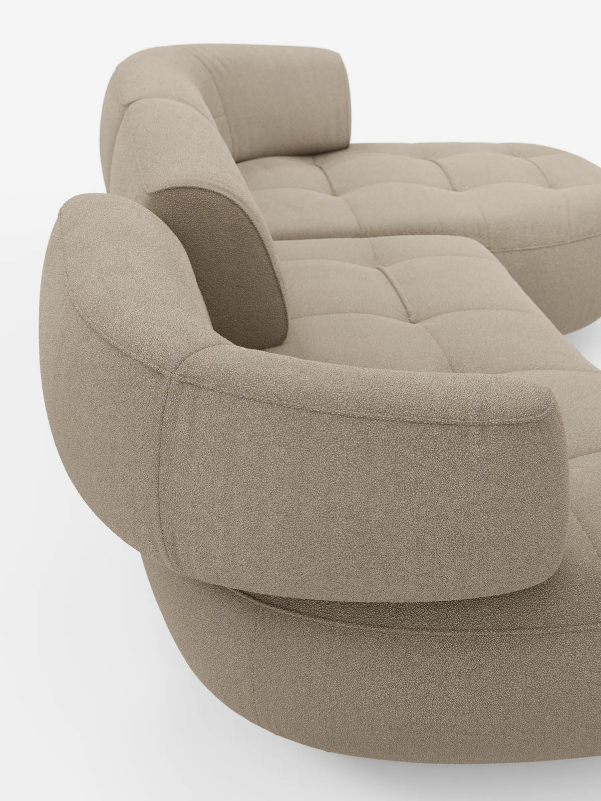 Un divano angolare Croissant dalla forma ricurva a fagiolo, con schienali scorrevoli in morbido tessuto smacchiabile T33 effetto cotone color beige testurizzato, caratterizzato da schienali arrotondati e cuscini trapuntati su sfondo bianco.