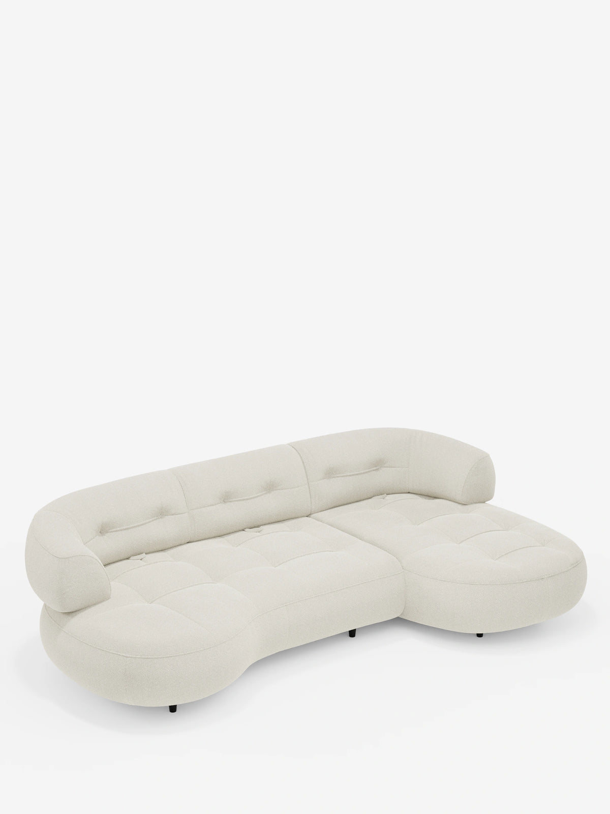 Un divano angolare Croissant color crema, dal design a forma di fagiolo, con schienali scorrevoli in morbido tessuto effetto cotone smacchiabile T33 con dettagli trapuntati, una silhouette dal profilo basso, schienale avvolgente e piccoli piedini neri.
