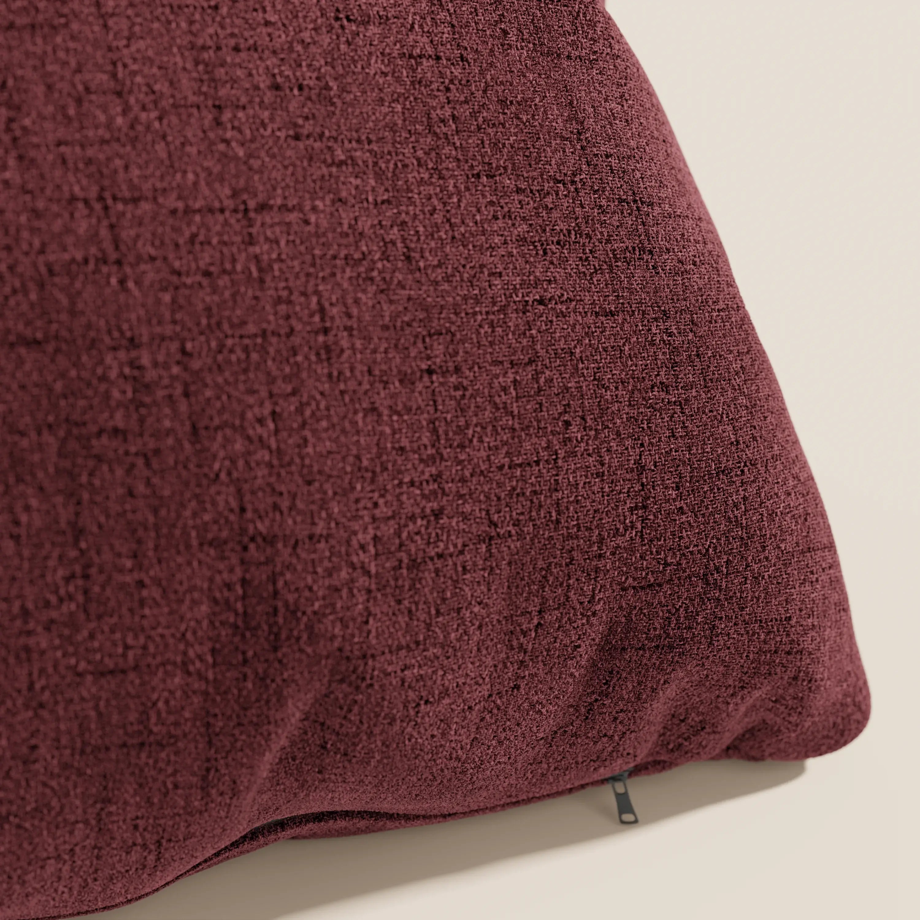 Un primo piano del cuscino Felis di Divani.Store, presentato in tessuto morbido impermeabile rosso T03, caratterizzato da una sottile trama a griglia e da una targhetta nera minimale, che ne sottolinea lo stile moderno e raffinato su uno sfondo chiaro.