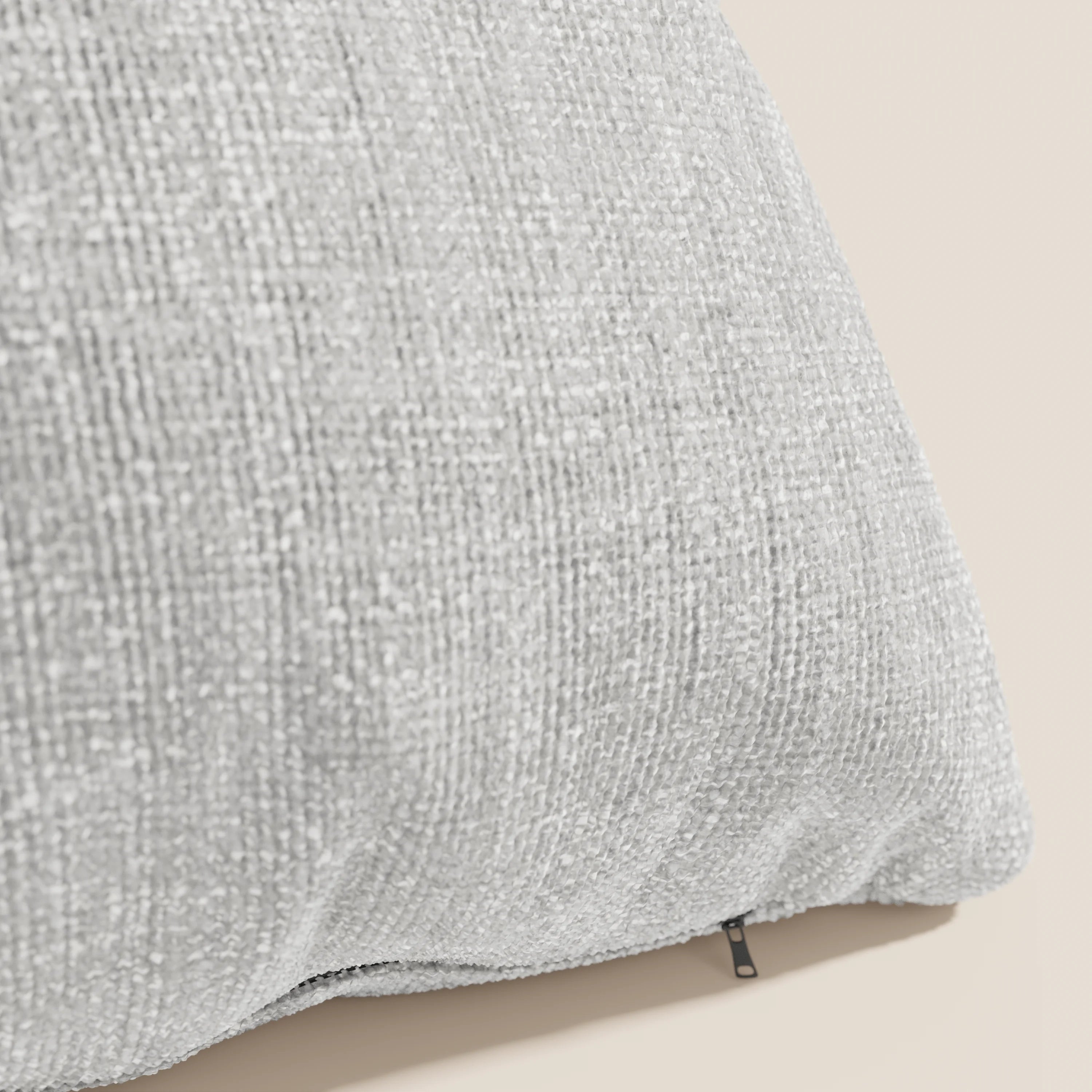 Primo piano del cuscino Lyon di Divani.Store, 45x45 cm, in T06 grigio: un tessuto morbido e resistente all'acqua, con un sottile motivo maculato e una discreta cerniera nera visibile sul bordo inferiore.
