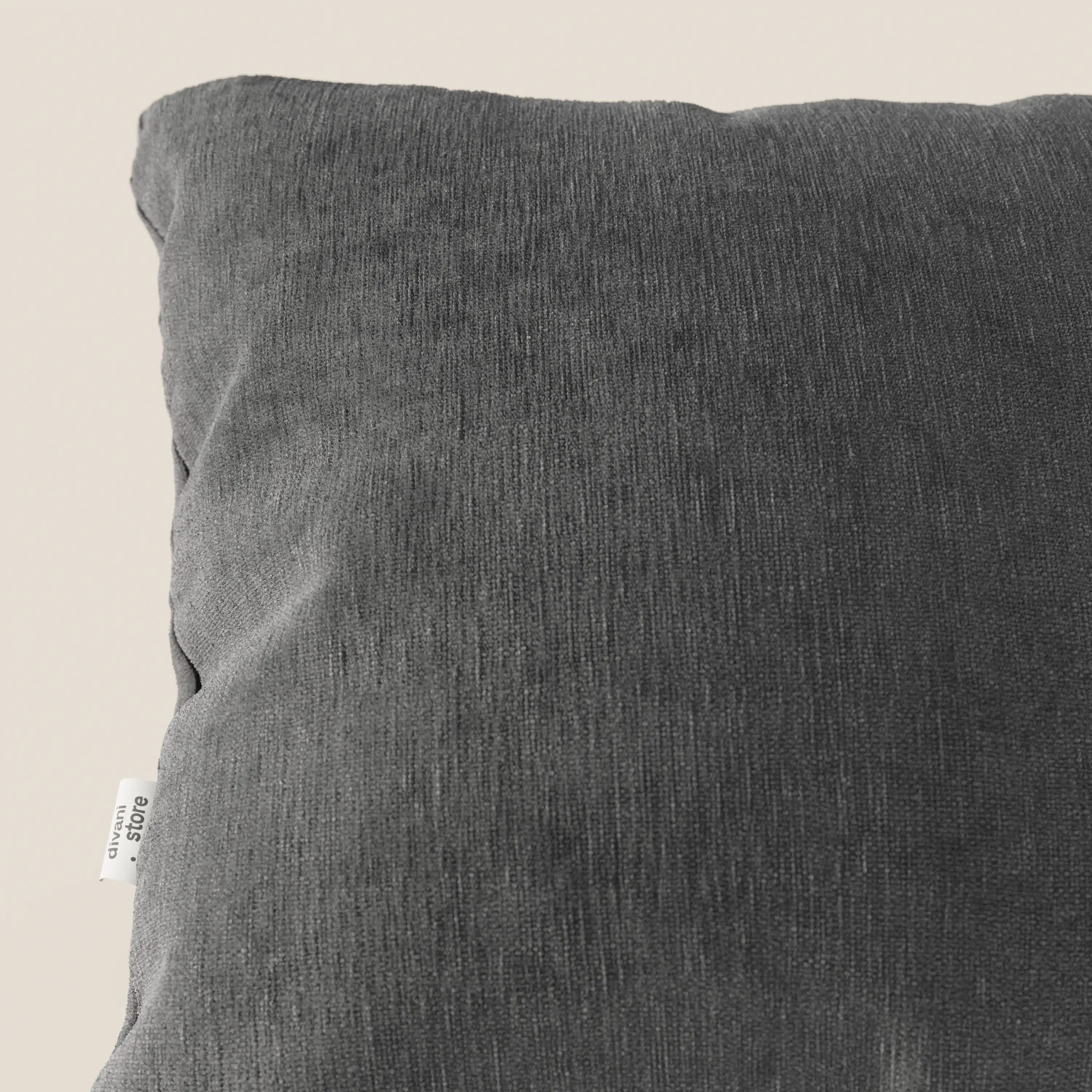 Primo piano del cuscino Bolero di Divani.Store in grigio scuro, con tessuto T31 morbido, strutturato e antimacchia. Una piccola etichetta bianca con testo nero è cucita nella cucitura sinistra. Lo sfondo è una tonalità neutra di beige chiaro.