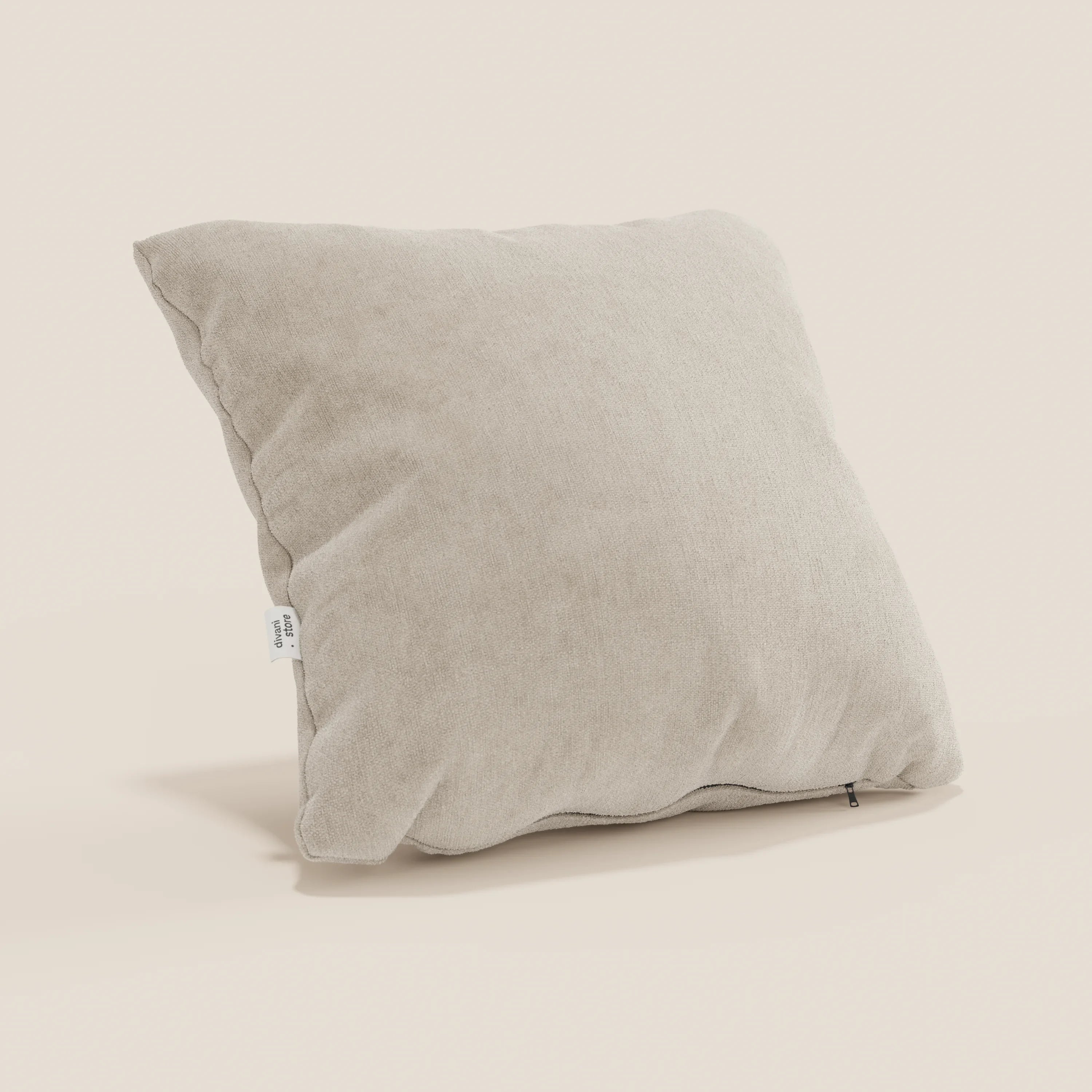 Il cuscino Bolero di Divani.Store, qui presentato in tessuto T31 beige chiaro, è leggermente abbondante, con etichetta bianca visibile e cerniera scura. Il morbido rivestimento, antimacchia, impermeabile e non restringente, poggia in posizione obliqua su un fondo bianco sporco.