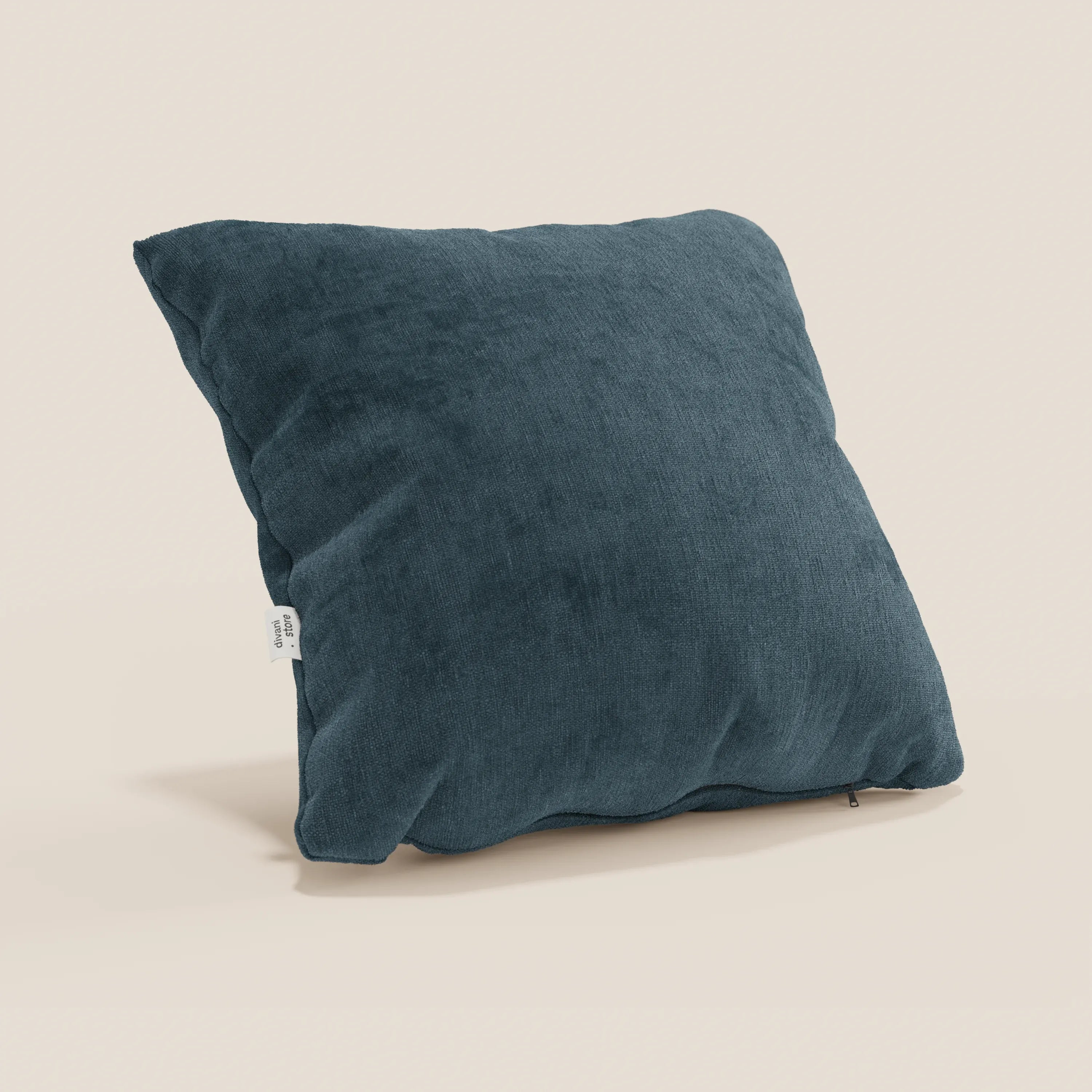 Un cuscino Bolero di Divani.Store in blu scuro, realizzato in morbido tessuto T31 antimacchia, impermeabile e non restringente, è appoggiato su una superficie beige chiaro con etichetta laterale visibile e aspetto felpato.
