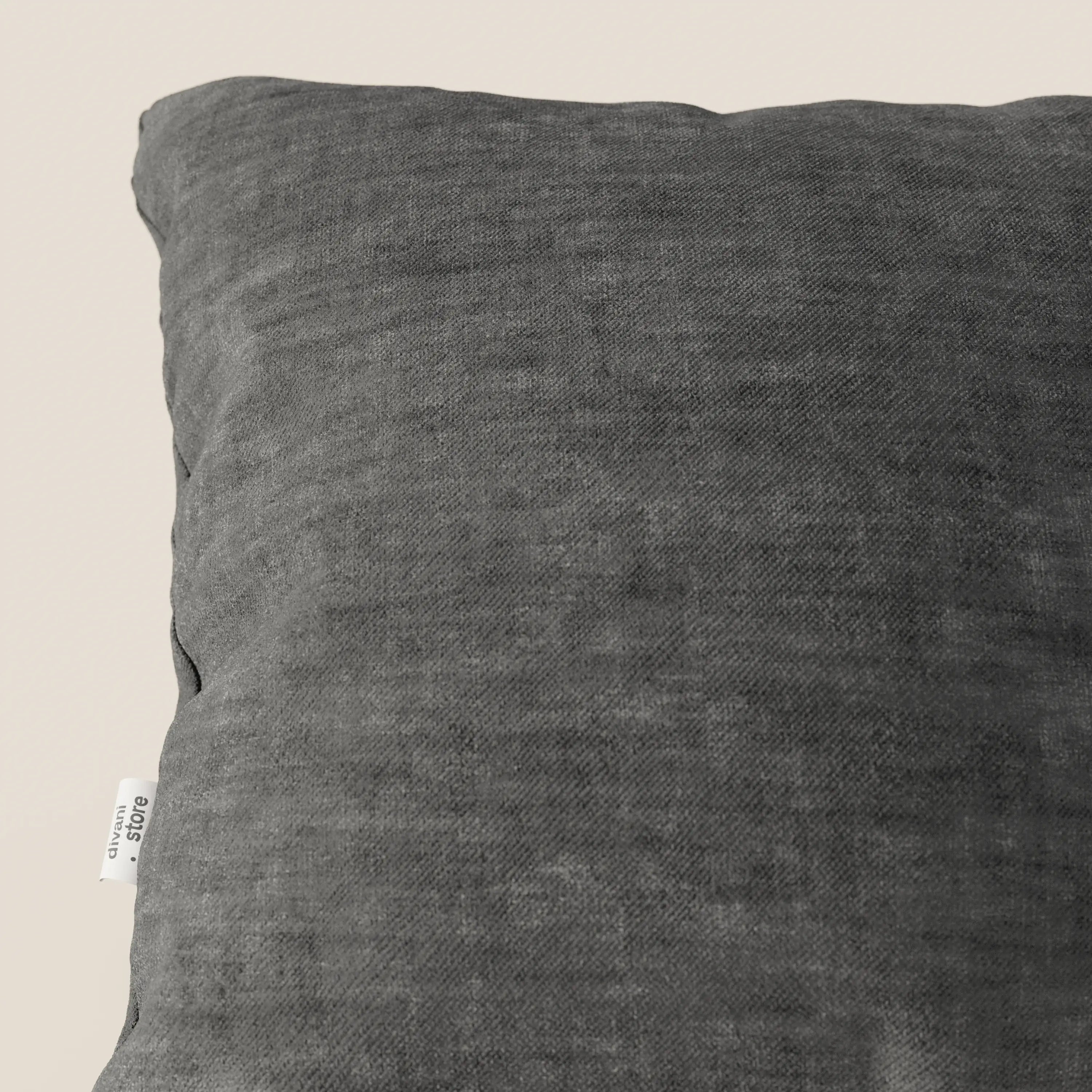 Primo piano del cuscino Sofia di Divani.Store in grigio scuro, realizzato in morbido velluto Easy Clean T35, antimacchia e impermeabile, con una piccola etichetta bianca sul lato. La texture felpata gli conferisce un aspetto accogliente sullo sfondo chiaro.