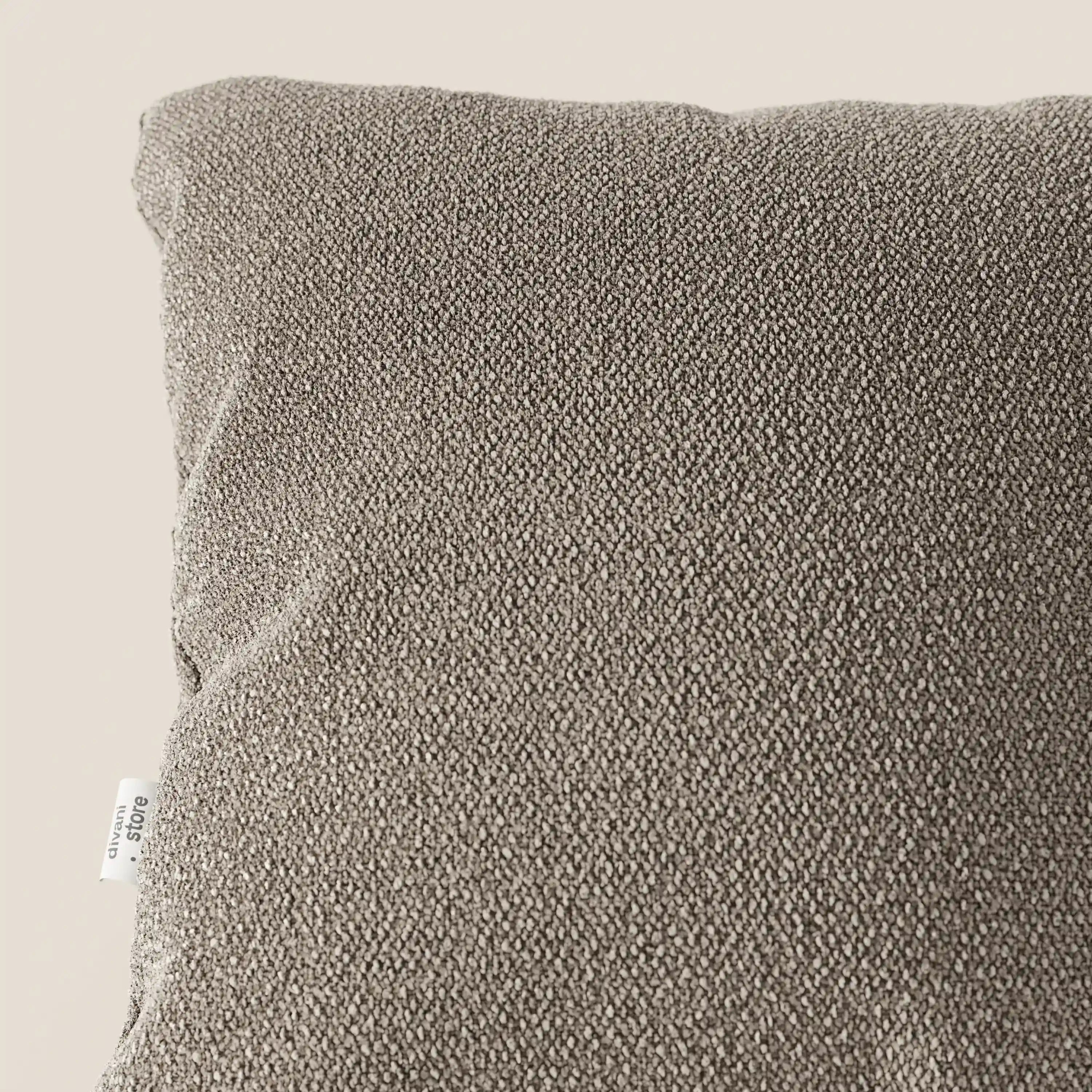 Primo piano del cuscino Lambada di Divani.Store in grigio tortora, realizzato in fresco tessuto T33 simile al cotone naturale, resistente alle macchie e all'acqua. Una piccola etichetta bianca è visibile sul cuscino quadrato morbido e strutturato su uno sfondo neutro.