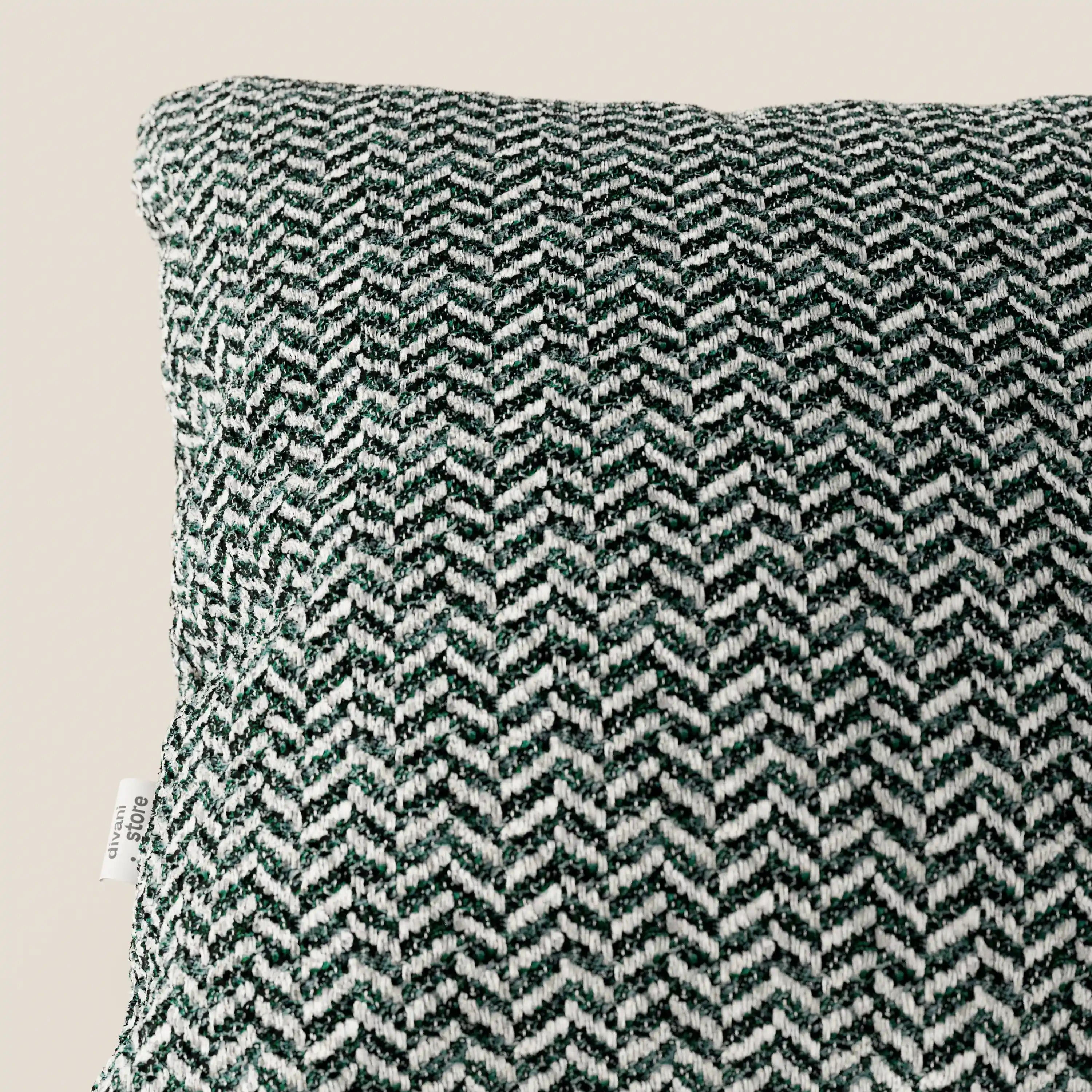 Un primo piano del cuscino Sorrento 45x45 in lino di Divani.Store ne mette in risalto la trama a spina di pesce in bianco e nero, una piccola etichetta bianca sul bordo sinistro e uno sfondo beige chiaro a tinta unita.