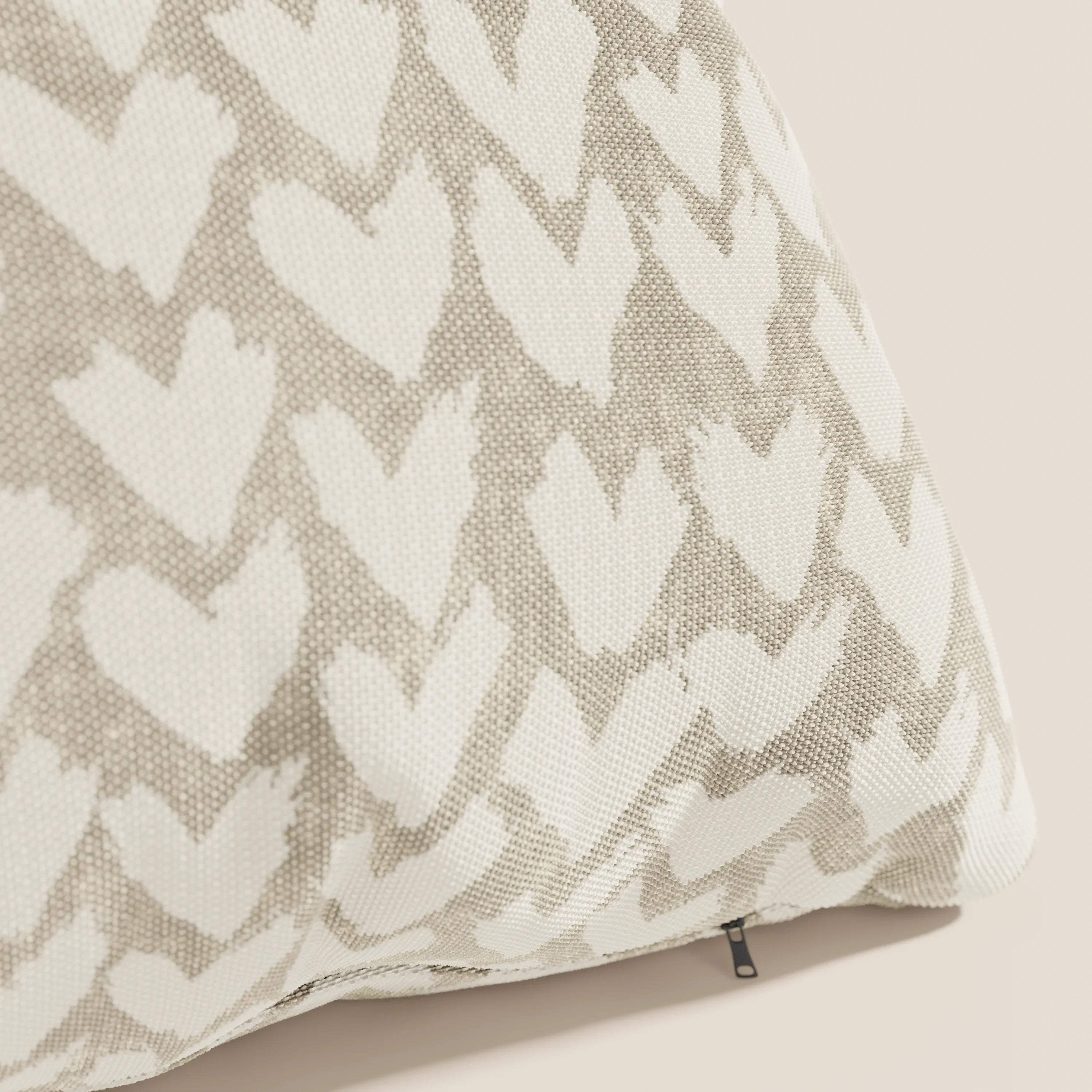 Primo piano dei cuscini geometrici Arrow di Divani.Store in beige, caratterizzati da forme di cuore disegnate a mano in bianco, una sottile trama intrecciata, un cuscino decorativo e una cerniera sul fondo. Realizzati in tessuto idrorepellente e presentati su sfondo chiaro.