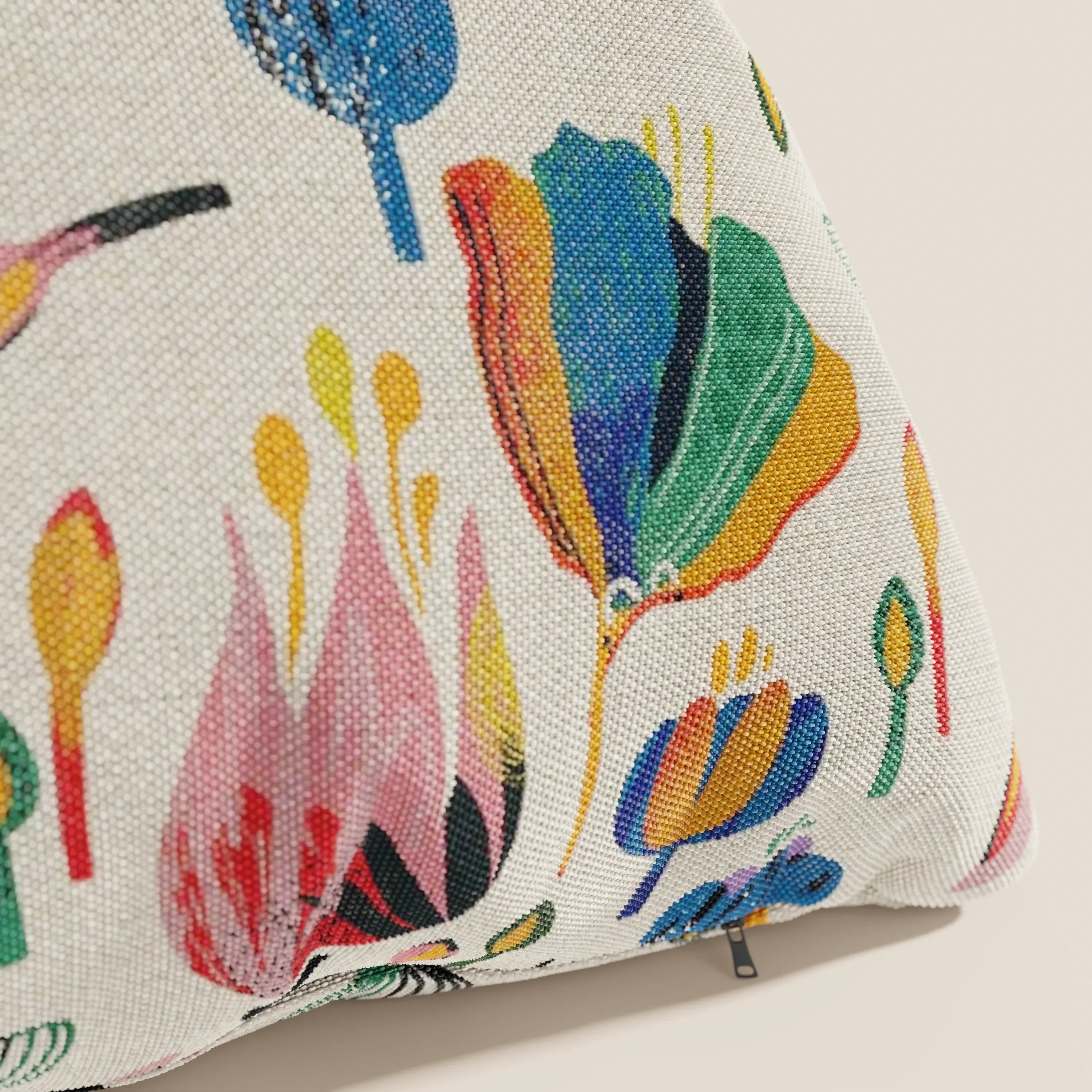 Un primo piano del cuscino Joy 45x45 cm di Divani.Store, della collezione a fantasie multicolor in tessuto fresco cotone impermeabile panna, mostra audaci motivi floreali astratti e una cerniera visibile sul coperchio lavabile.
