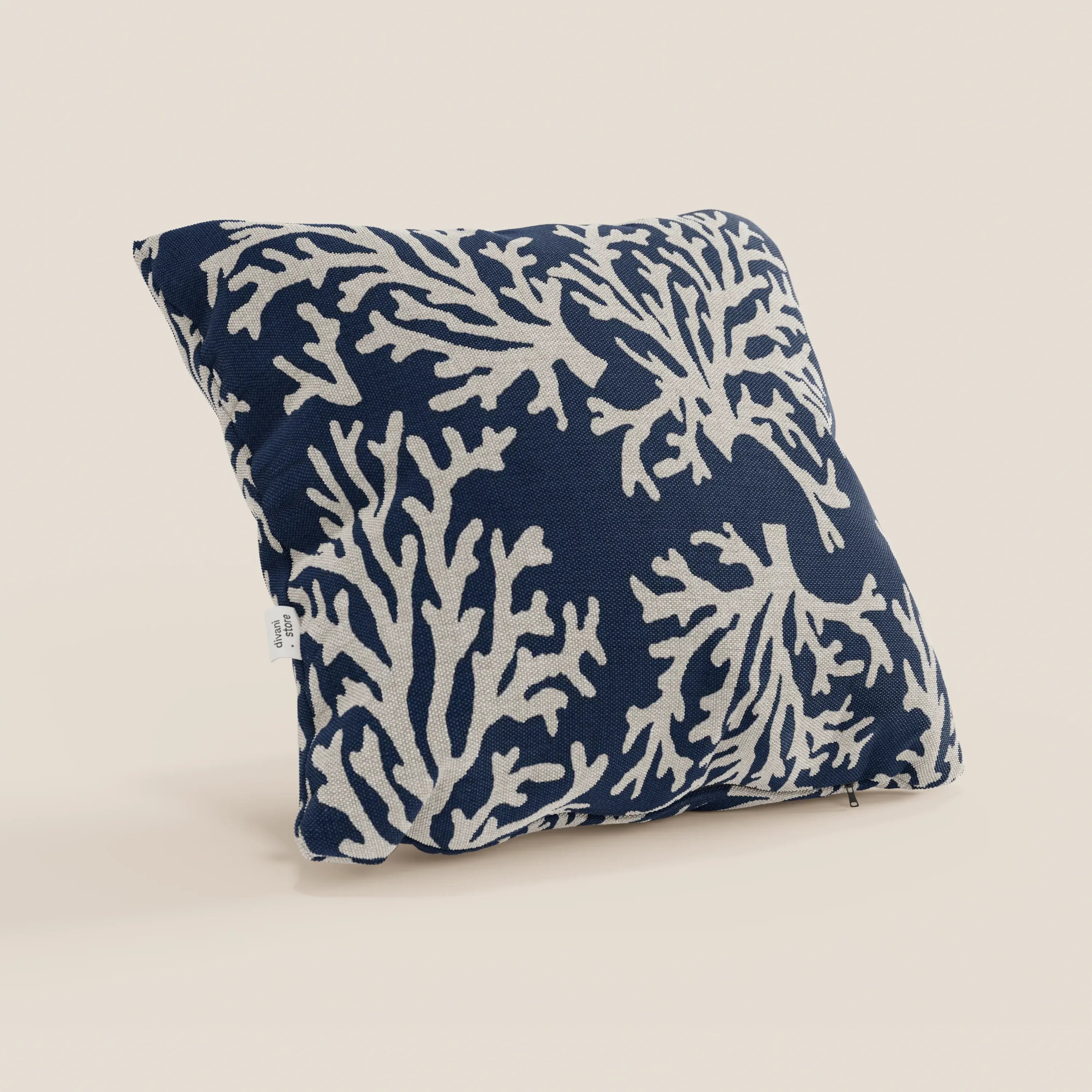 Il cuscino Nautilus 45x45 di Divani.Store è caratterizzato da un tessuto impermeabile blu navy con un disegno di barriera corallina color crema e un aspetto decorativo e felpato. Un'etichetta bianca è visibile sulla cucitura sinistra su uno sfondo neutro.