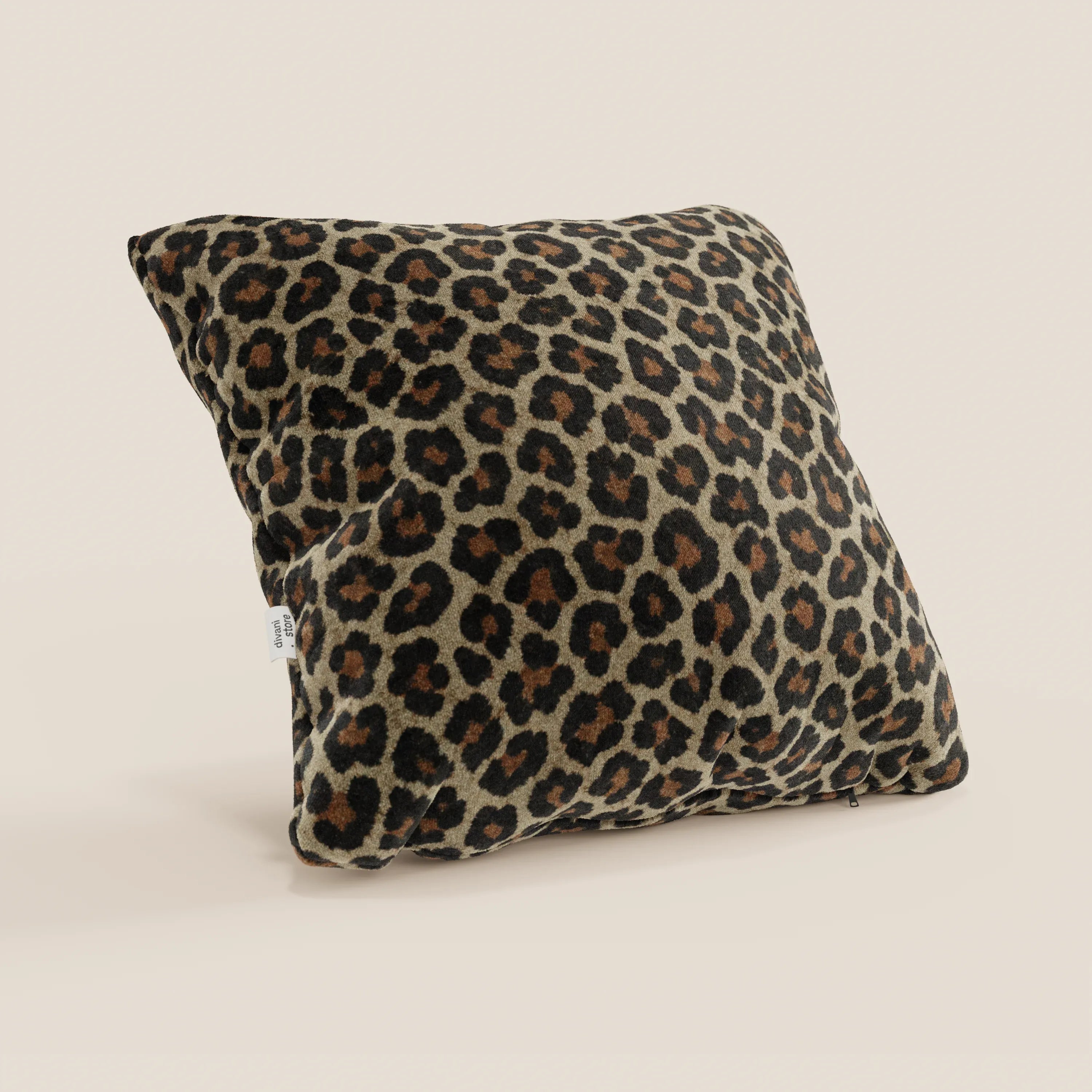 Il cuscino Wild della collezione Wild di Divani.Store è un cuscino quadrato in microfibra lavabile in lavatrice con una vistosa stampa leopardata marrone, nera e marrone chiaro su beige chiaro e una piccola etichetta laterale bianca.