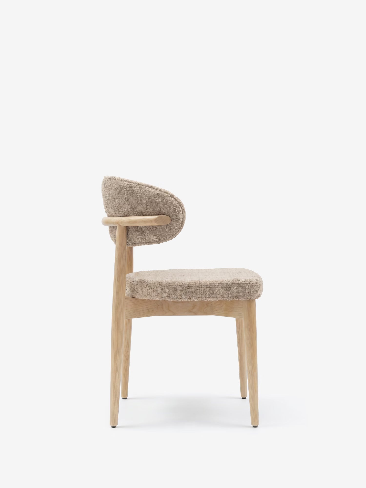 Vista laterale della sedia imbottita Dafne di Divani.Store, realizzata in rovere naturale massello con gambe in legno chiaro e schienale e seduta arrotondati, rivestiti in ciniglia beige certificata OEKO-TEX®, raffigurata su uno sfondo bianco a tinta unita.