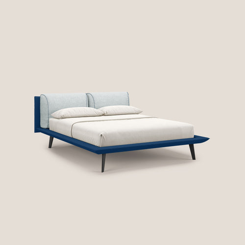 Il letto di design Petra di Letti.store è caratterizzato dal tessuto impermeabile bicolore T11 e T06 nei colori blu e ghiaccio, dai cuscini in piuma e dai piedini in mogano, presentati con biancheria da letto bianca e uno sfondo beige minimal per un look moderno e contemporaneo.