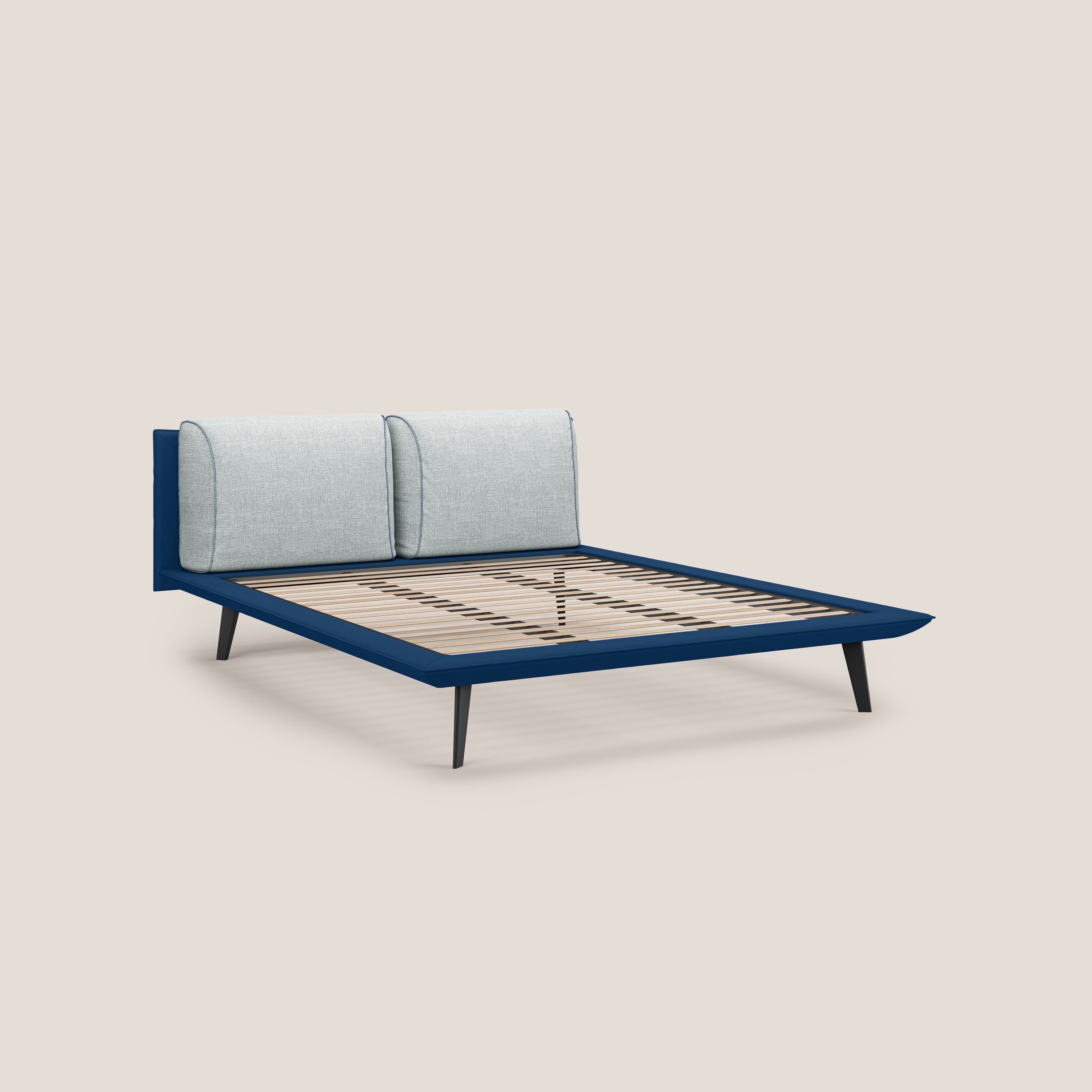 Il letto di design Petra di Letti.store è caratterizzato dal tessuto bicolore impermeabile T11 blu e T06 ghiaccio, dai cuscini in piuma, dai piedini in mogano ed è presentato senza materasso o biancheria su uno sfondo beige.