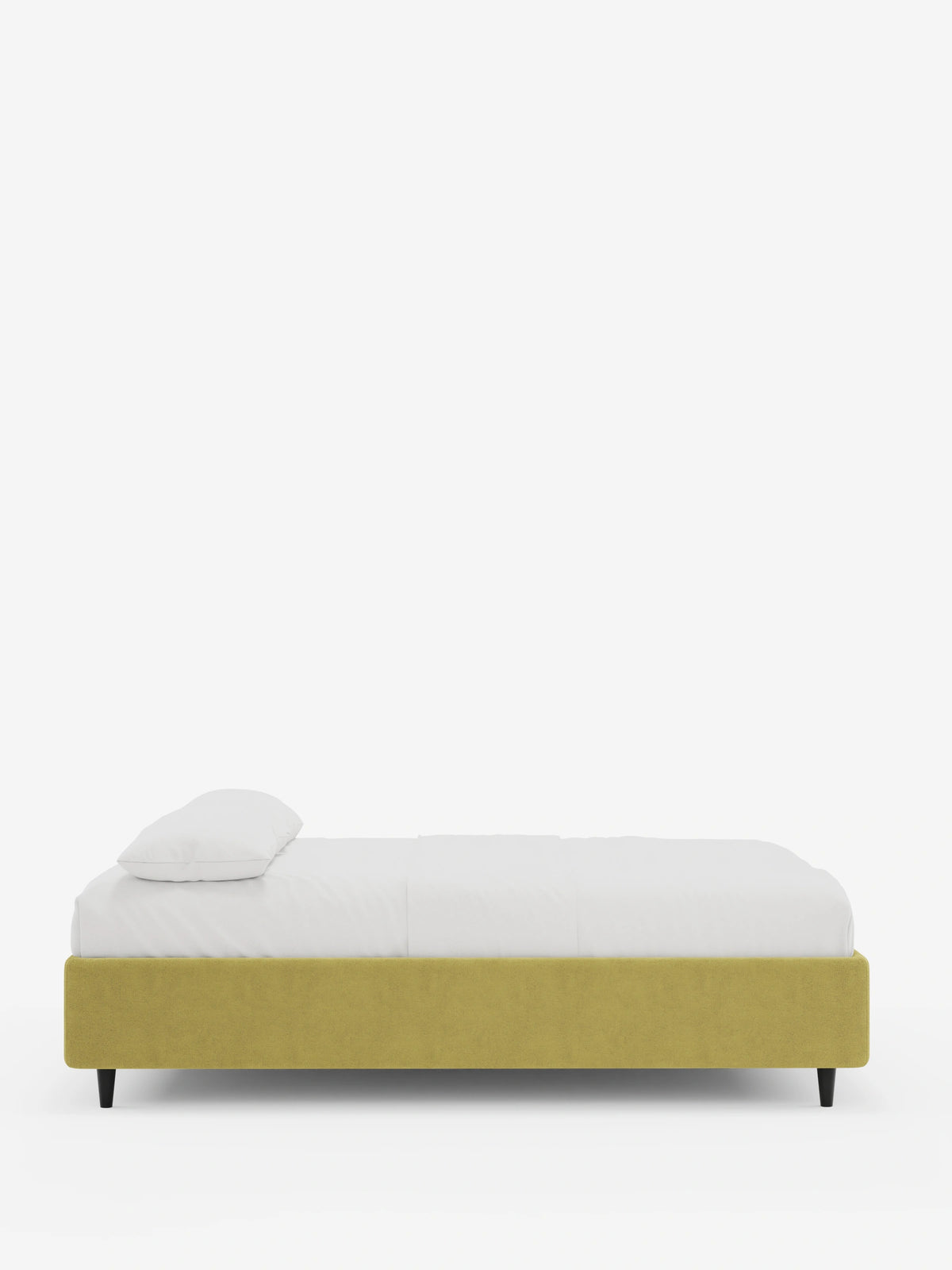 Il letto sommier imbottito ERON con contenitore in tessuto impermeabile certificato Oeko-Tex è un letto imbottito di colore giallo senape, sostenuto da quattro gambe affusolate scure, con biancheria da letto bianca e un unico cuscino su uno sfondo bianco sporco.