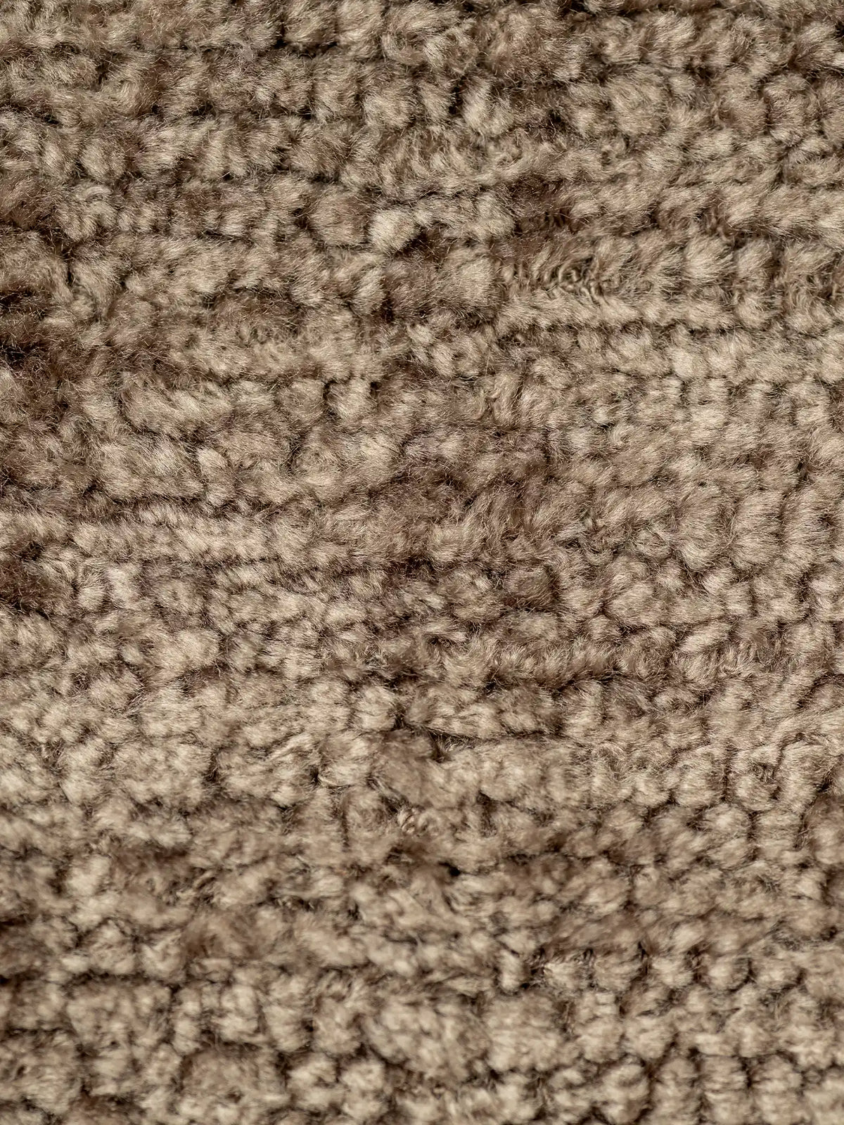 Primo piano su S02 ELITE, un tessuto bouclé materico strutturato e smacchiabile in ciniglia, di colore taupe, con un pelo denso a riccioli che crea una superficie irregolare e avvolgente, caratterizzata da varie tonalità di marrone e grigio.