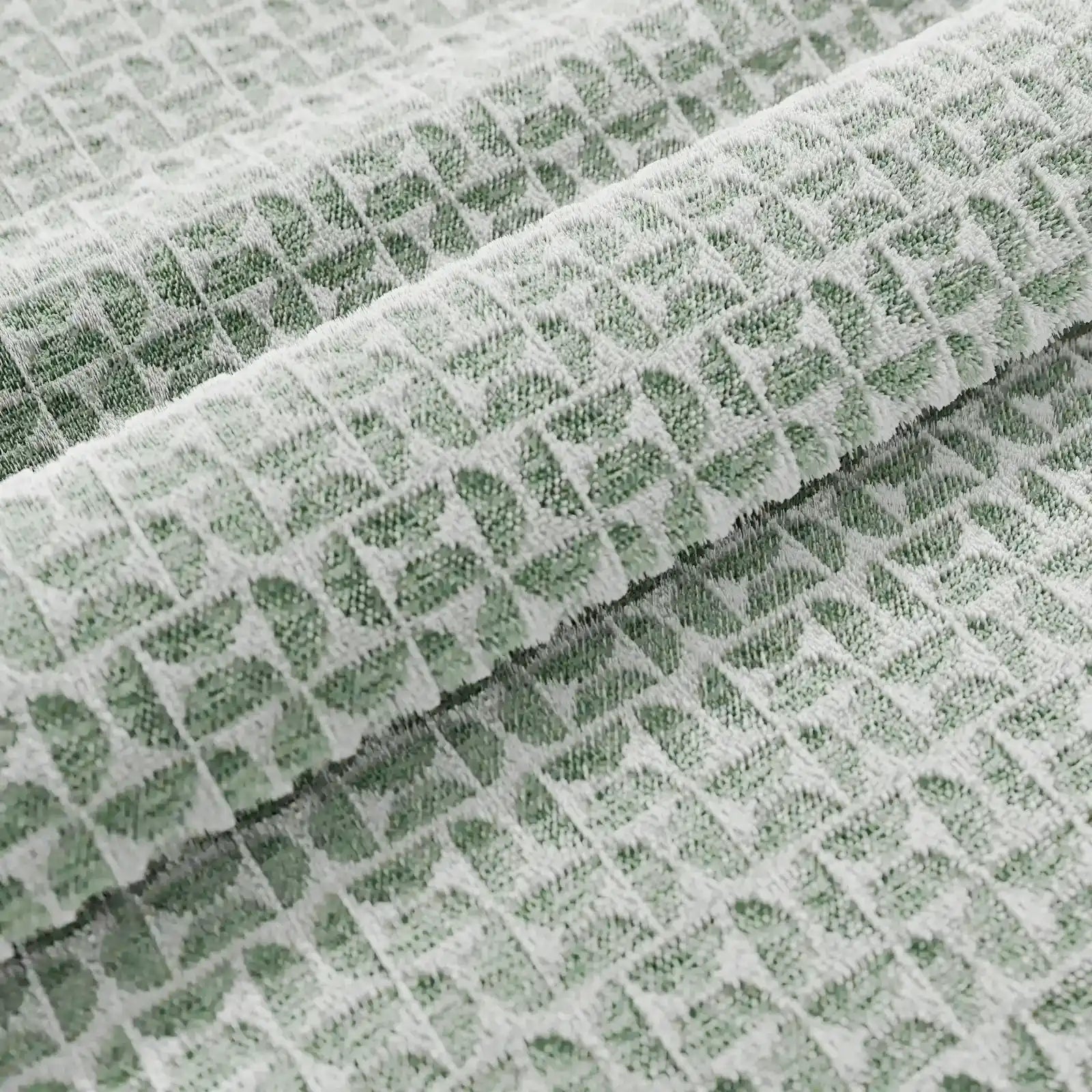 Un primo piano del modello Naxos Cuscino Decoro 45x45 in lino di Divani.Store mostra un tessuto verde chiaro con un motivo geometrico a quadrati in rilievo e una trama simile a quella di una cialda: ideale per un arredamento elegante e raffinato.