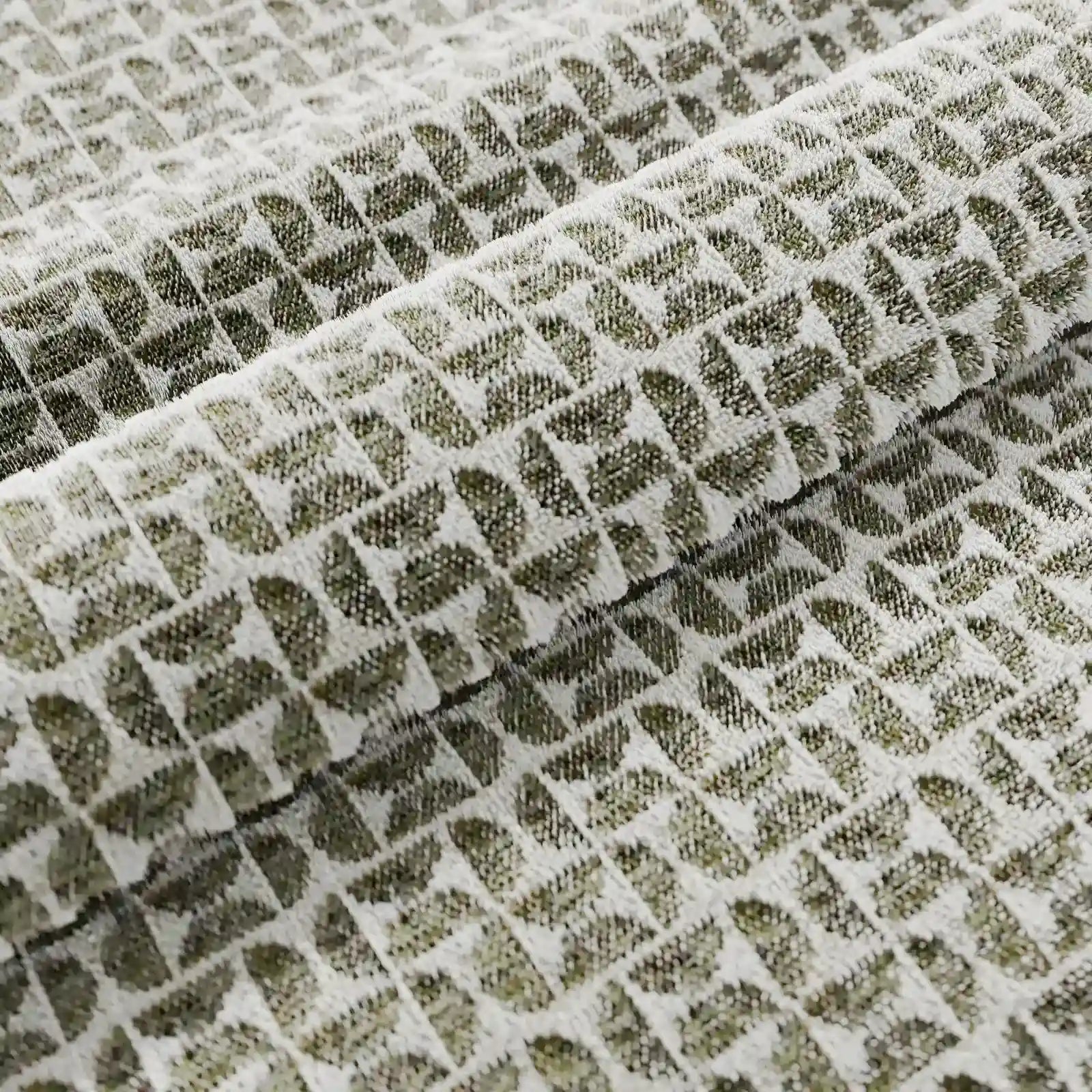Un primo piano del cuscino Naxos Cuscino Decoro 45x45 in lino di Divani.Store ne rivela la trama del lino, i delicati motivi geometrici a triangoli su uno sfondo verde-grigio tenue e le morbide pieghe: un elegante cuscino quadrato perfetto per un arredamento di classe.