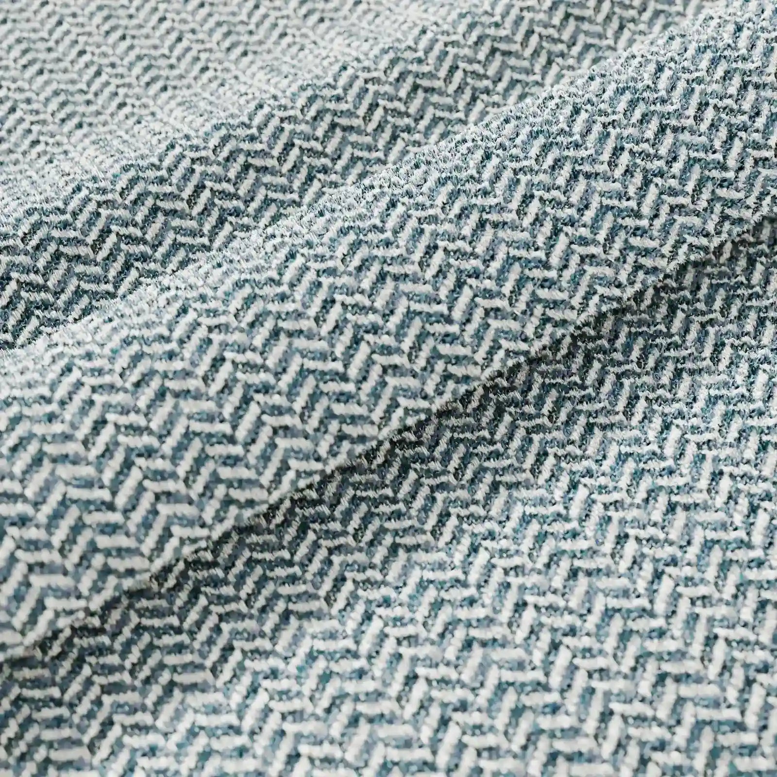 Primo piano del cuscino Sorrento 45x45 in lino di Divani.Store, caratterizzato da un motivo a zigzag chevron nei toni dell’azzurro e del bianco, ideale per l’uso all’aperto. Le morbide pieghe mettono in risalto la trama di alta qualità e l’elegante disegno geometrico.